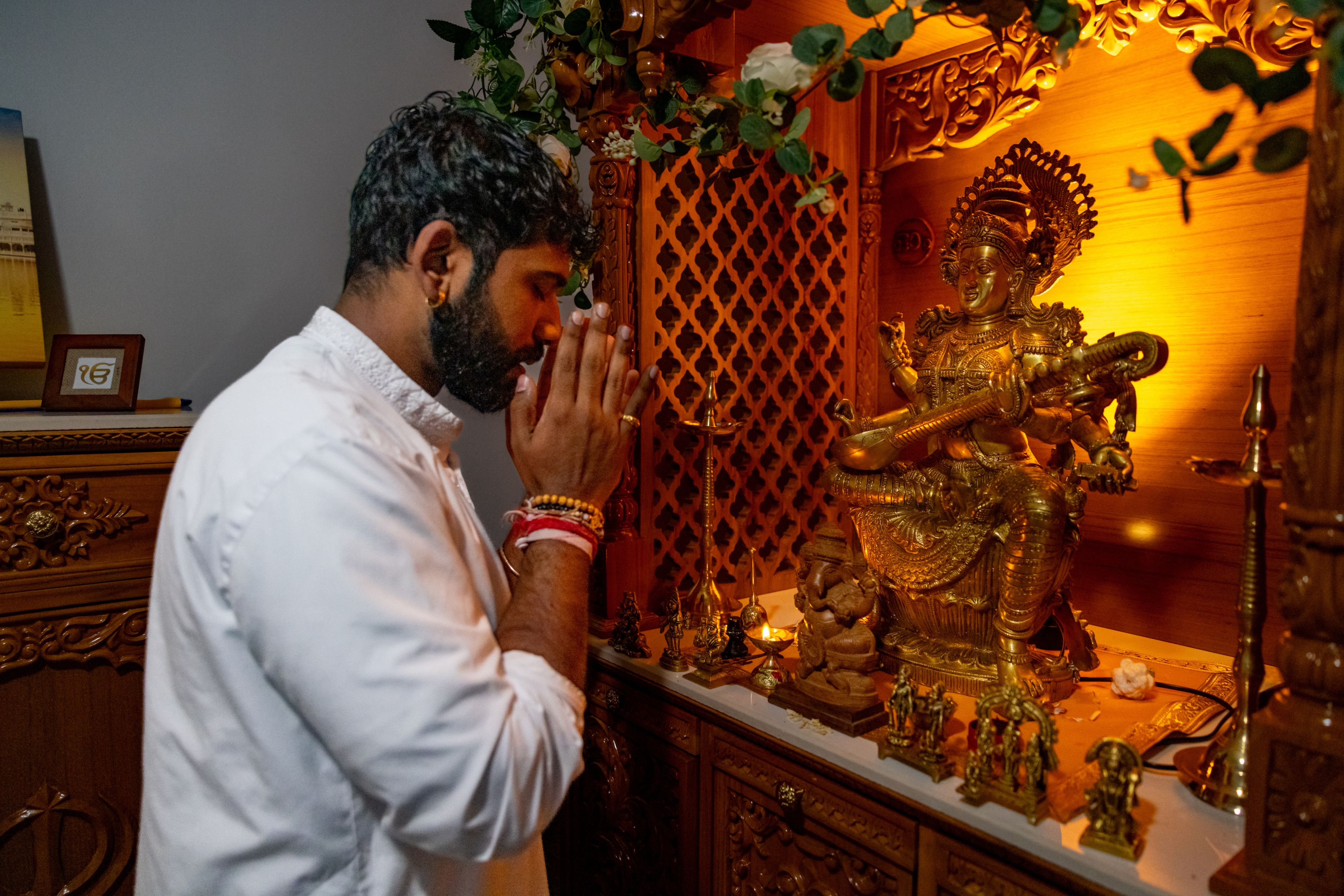 Rajeev Persaud kneeling and praying at Hindu shrine. 
