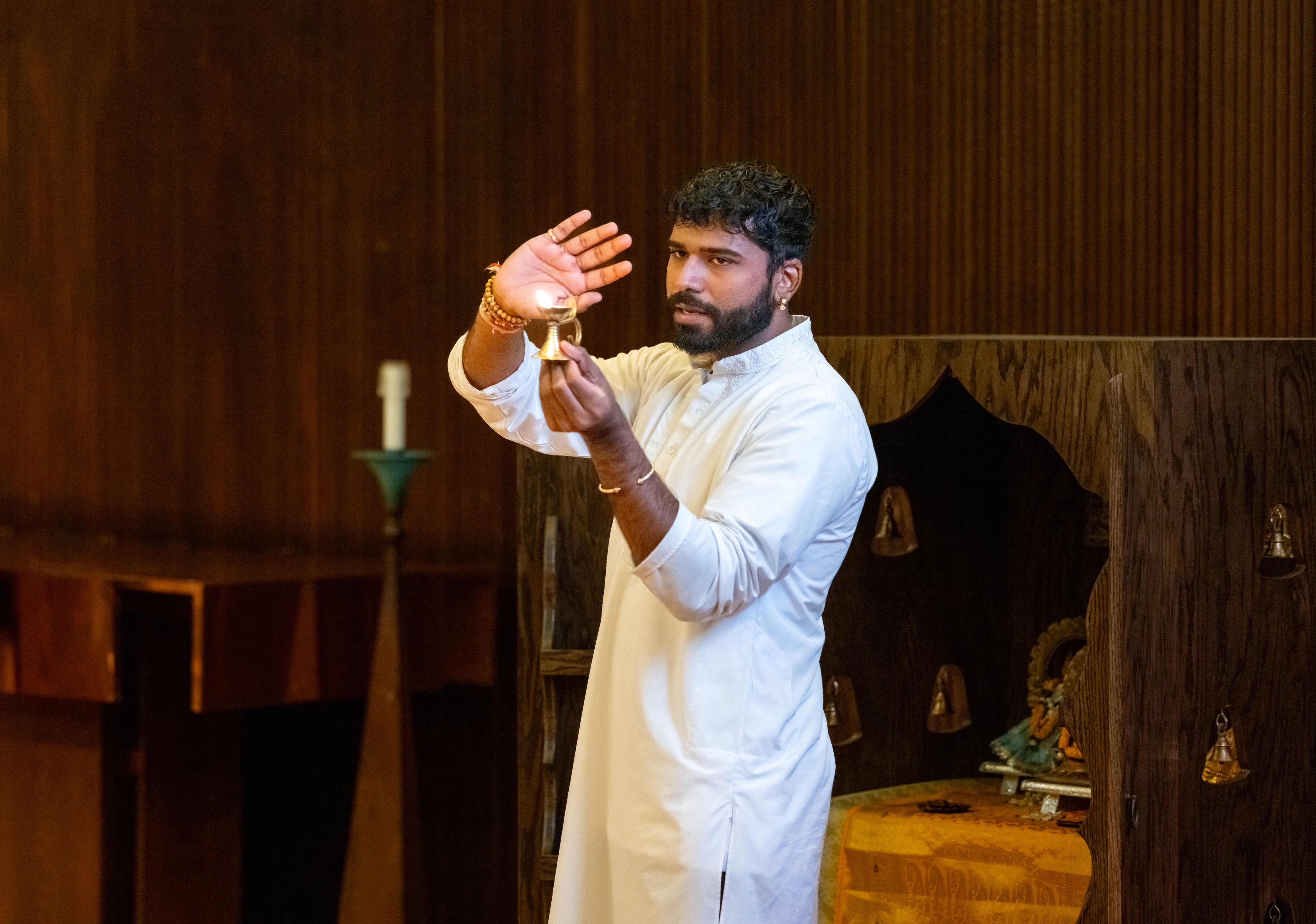 Persaud holding hand next to lit lamp