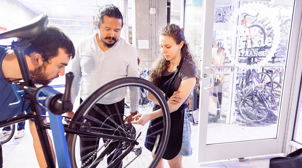 Photo of Emory students watching a bike being fixed.