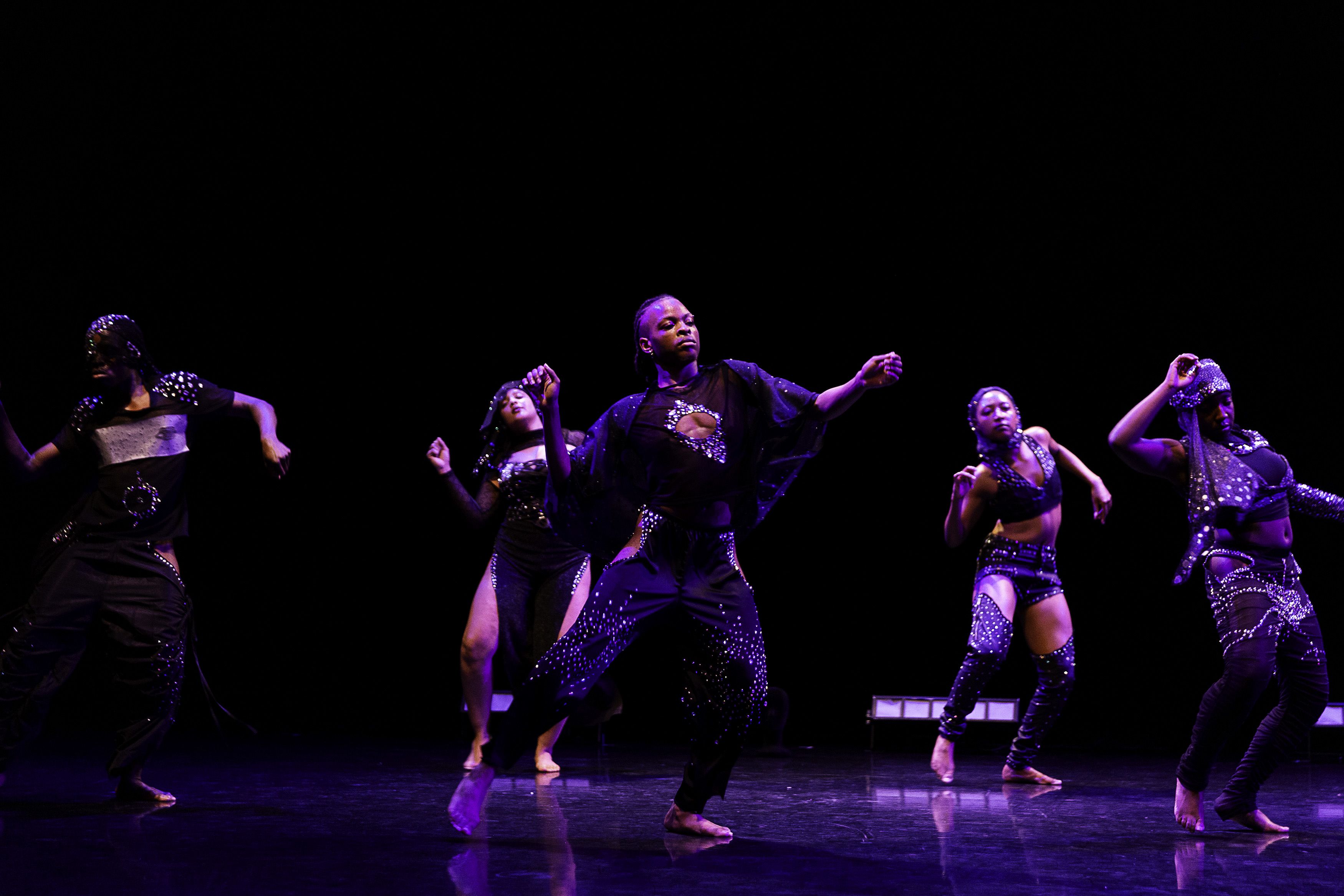 Five costumed dancers move in synch.