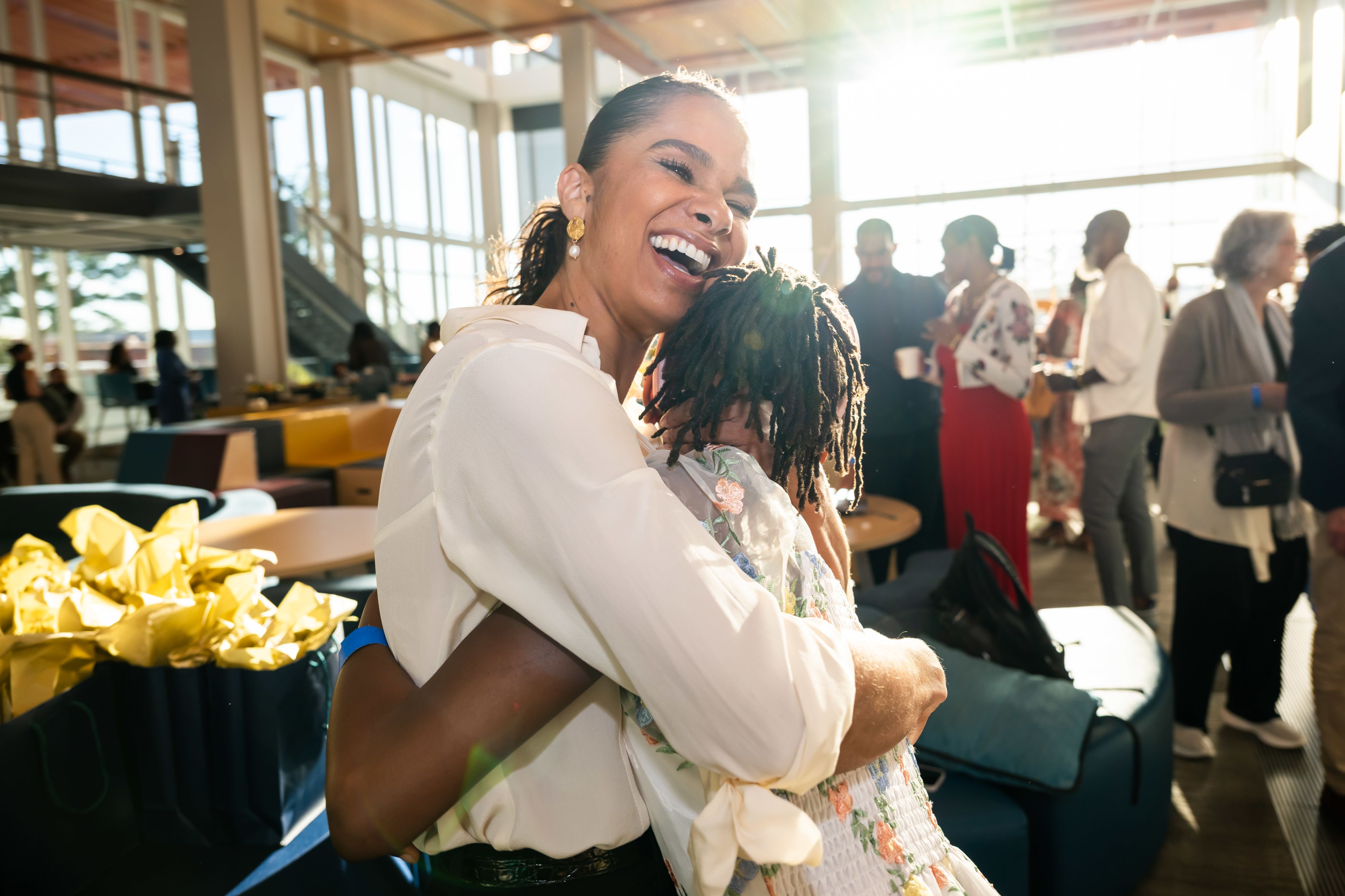 A child embraces a woman who smiles broadly.