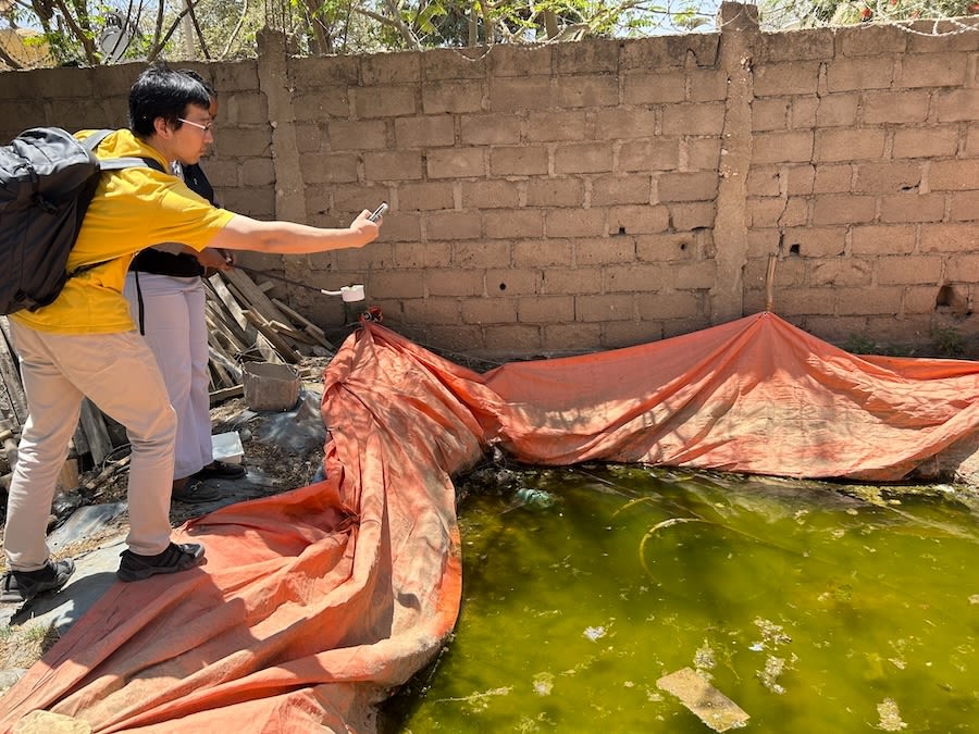 Xiao Huang records the GPS coordinates for a construction site cistern containing algae.