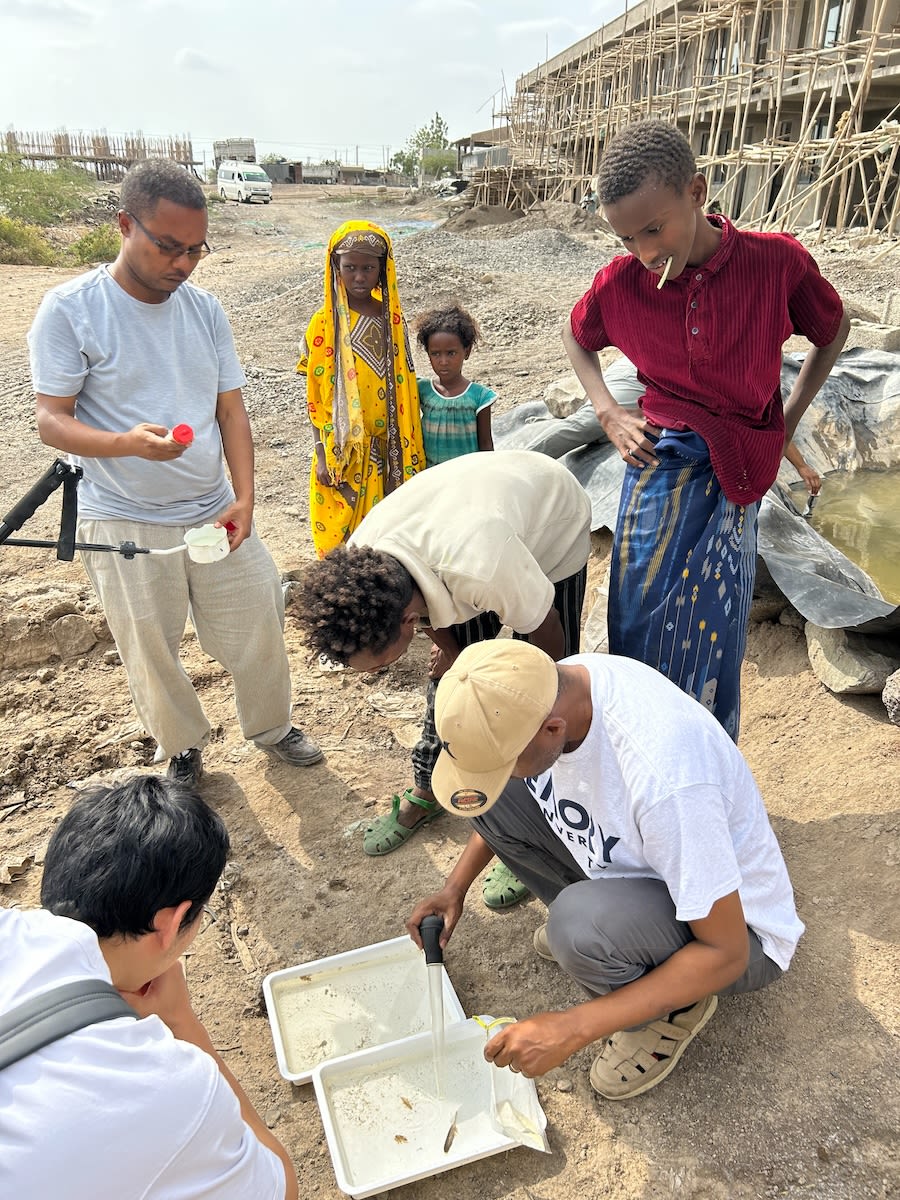 Curious children gather to watch the researchers at work in the field.