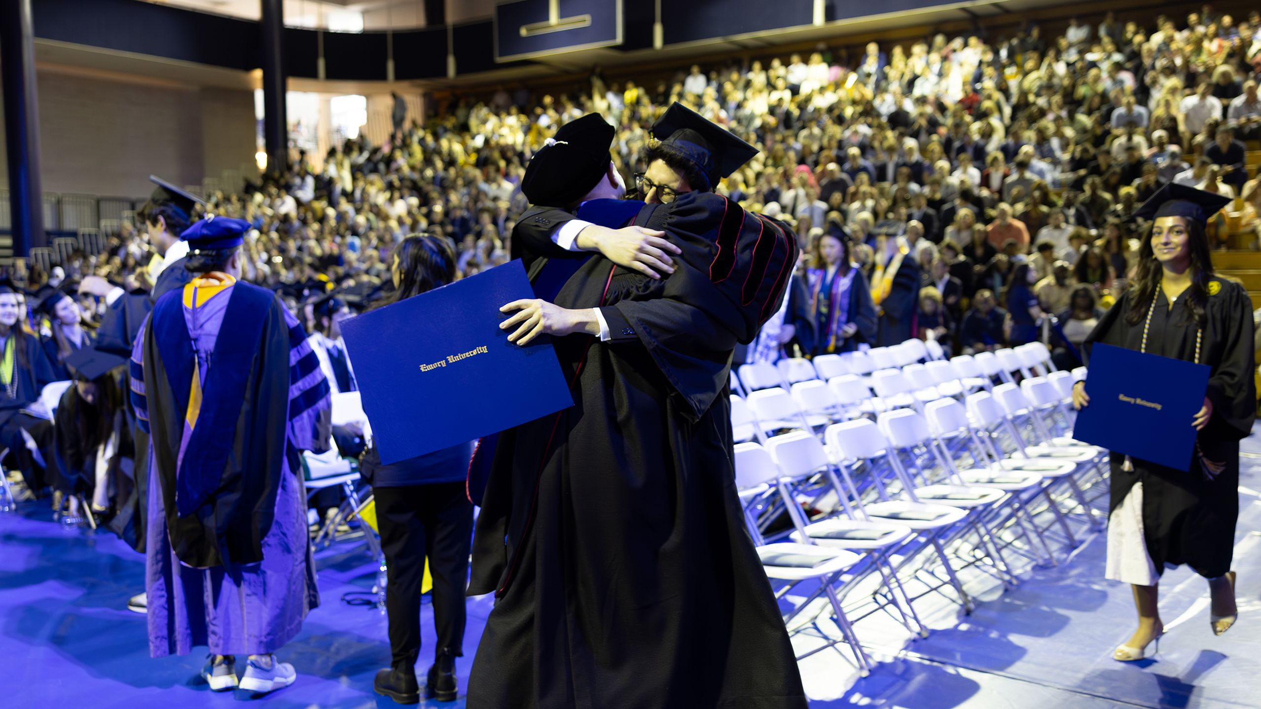 A graduate hugs a professor after receiving his degree
