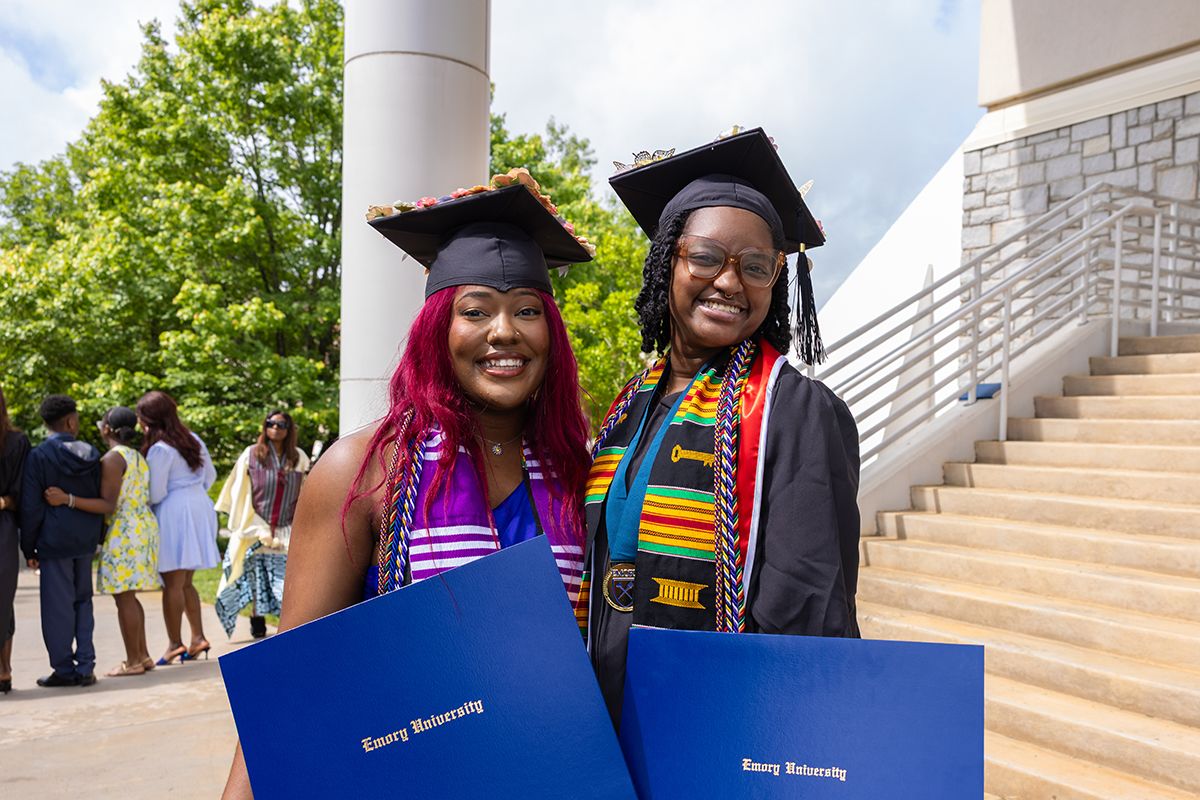 Students with bright stoles pose with their diplomas