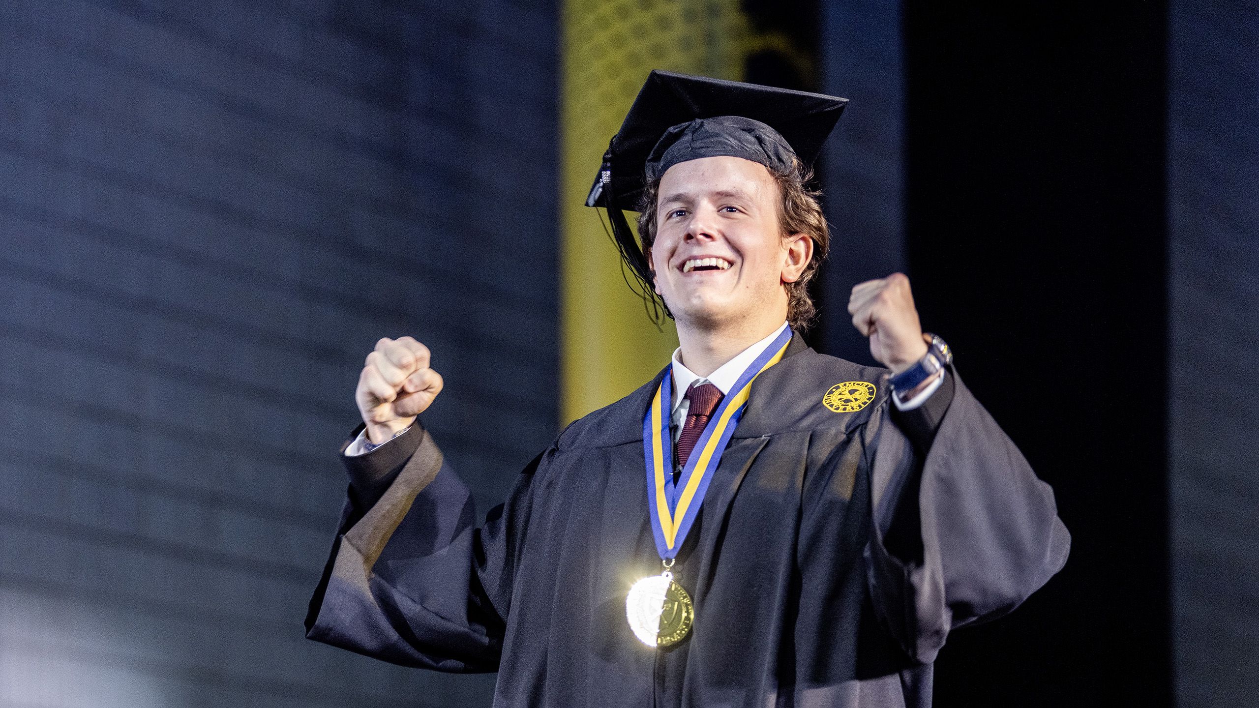 A graduate cheers as he crosses the stage