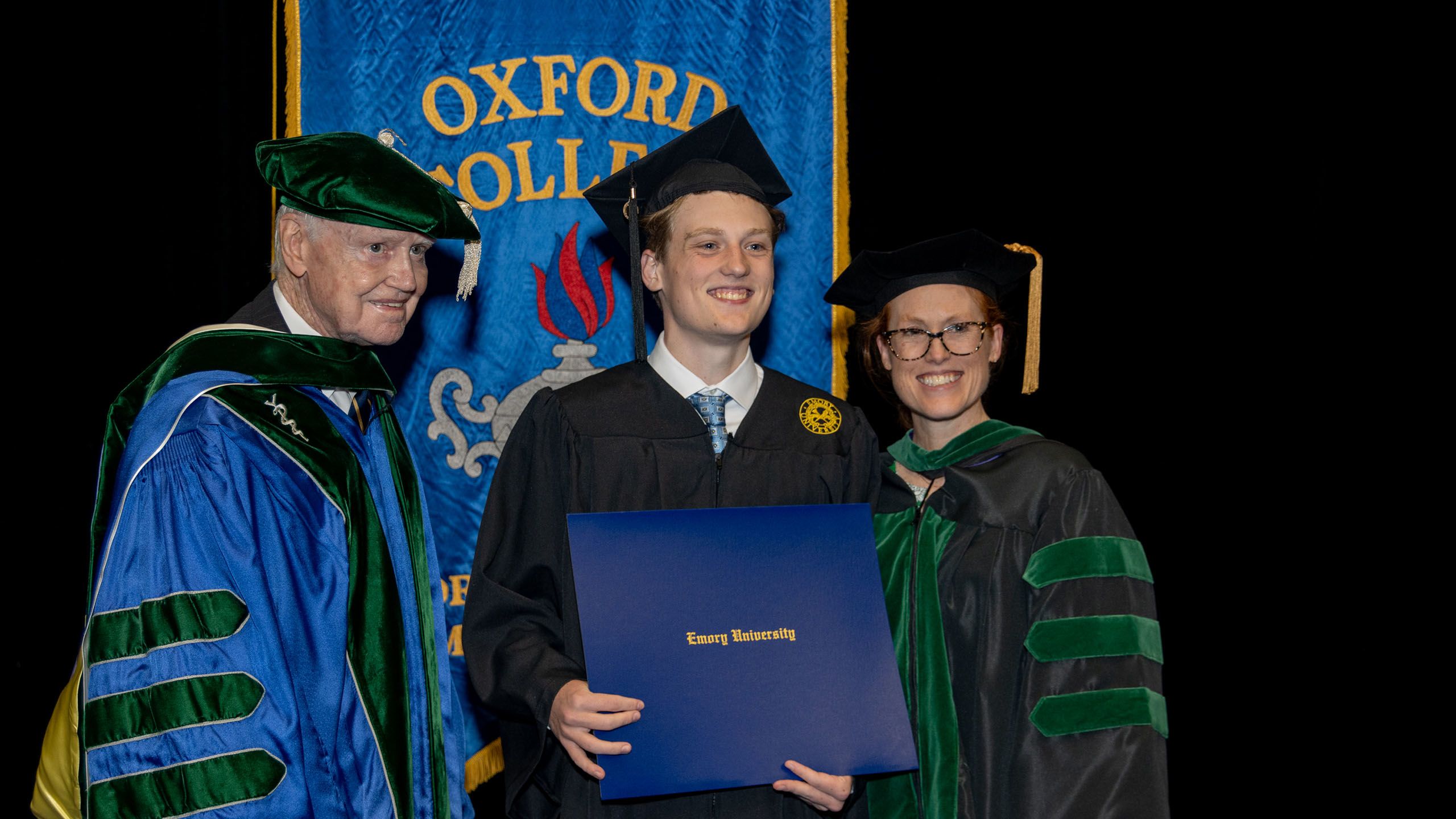 A student poses with family members in academic regalia