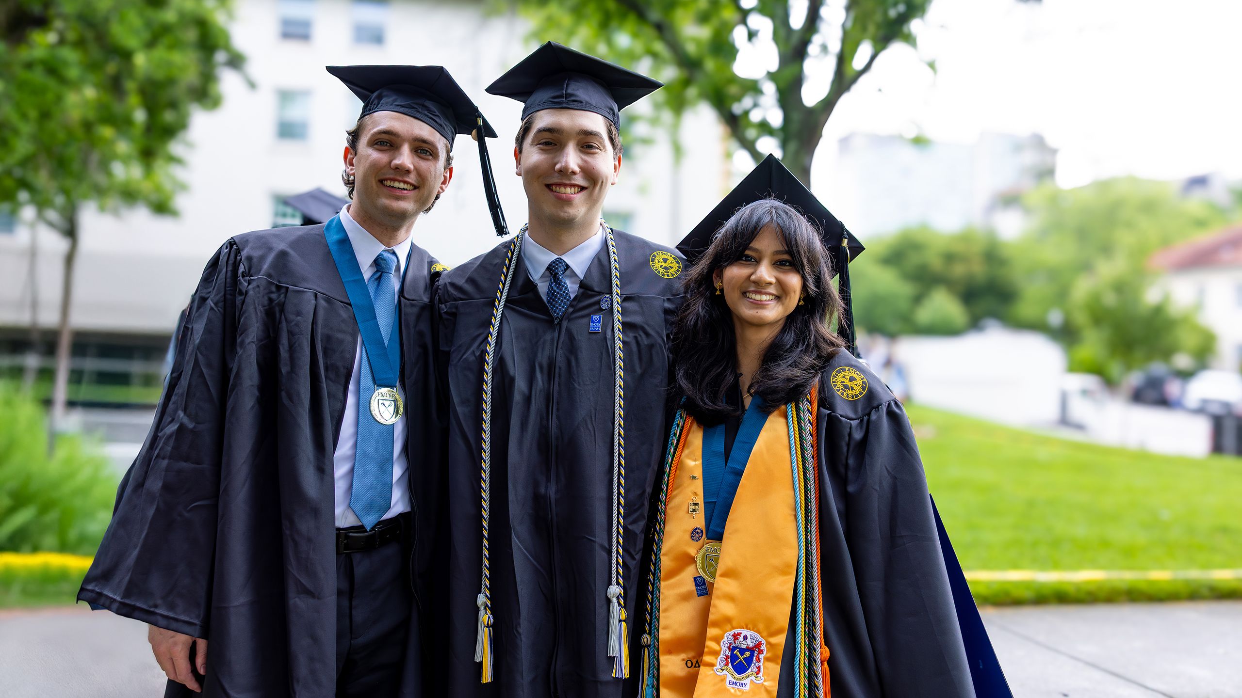 Three friends pose in graduation caps and gowns