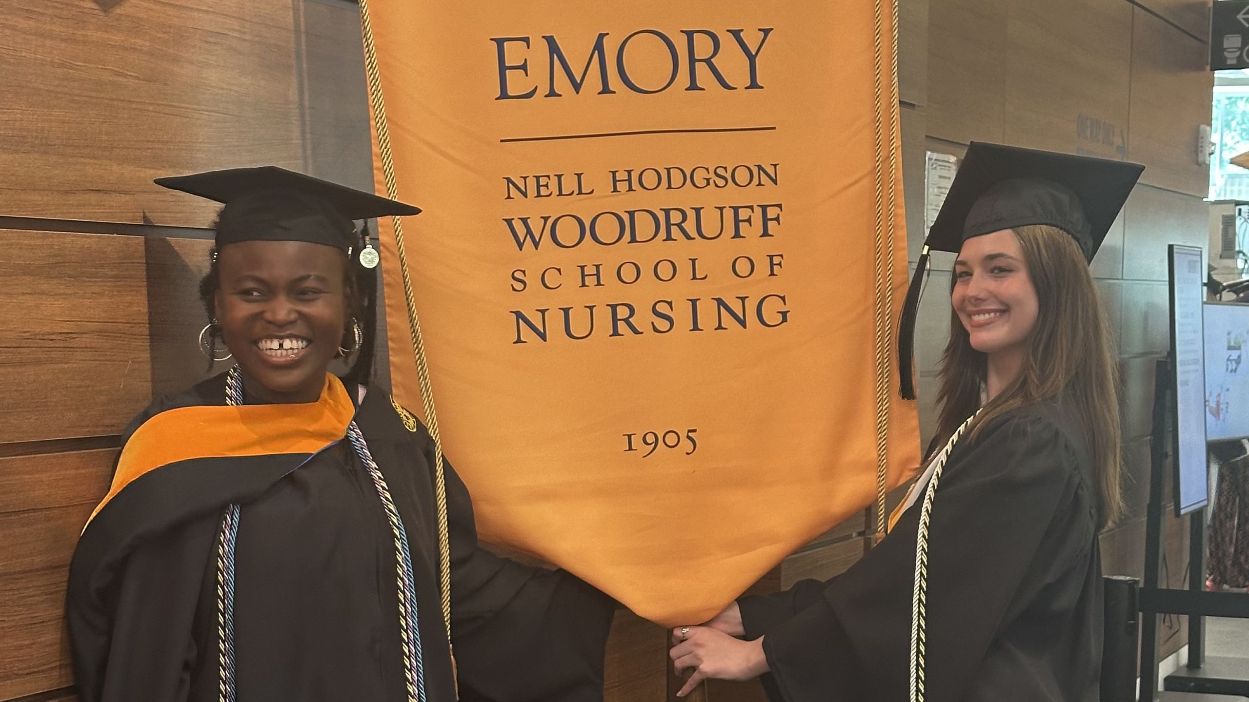 Two students hold the School of Nursing banner