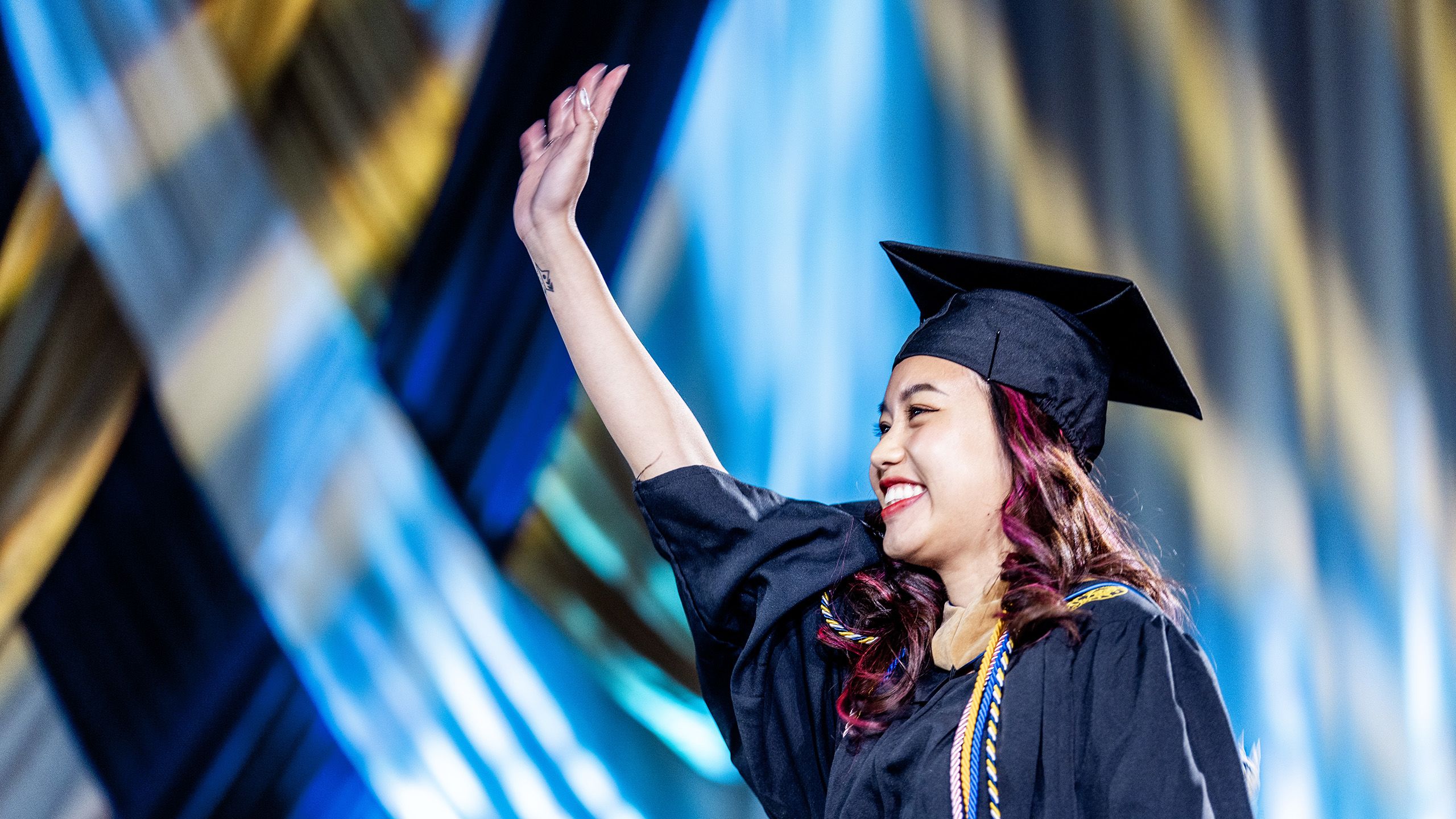 A graduate waves as she crosses the stage