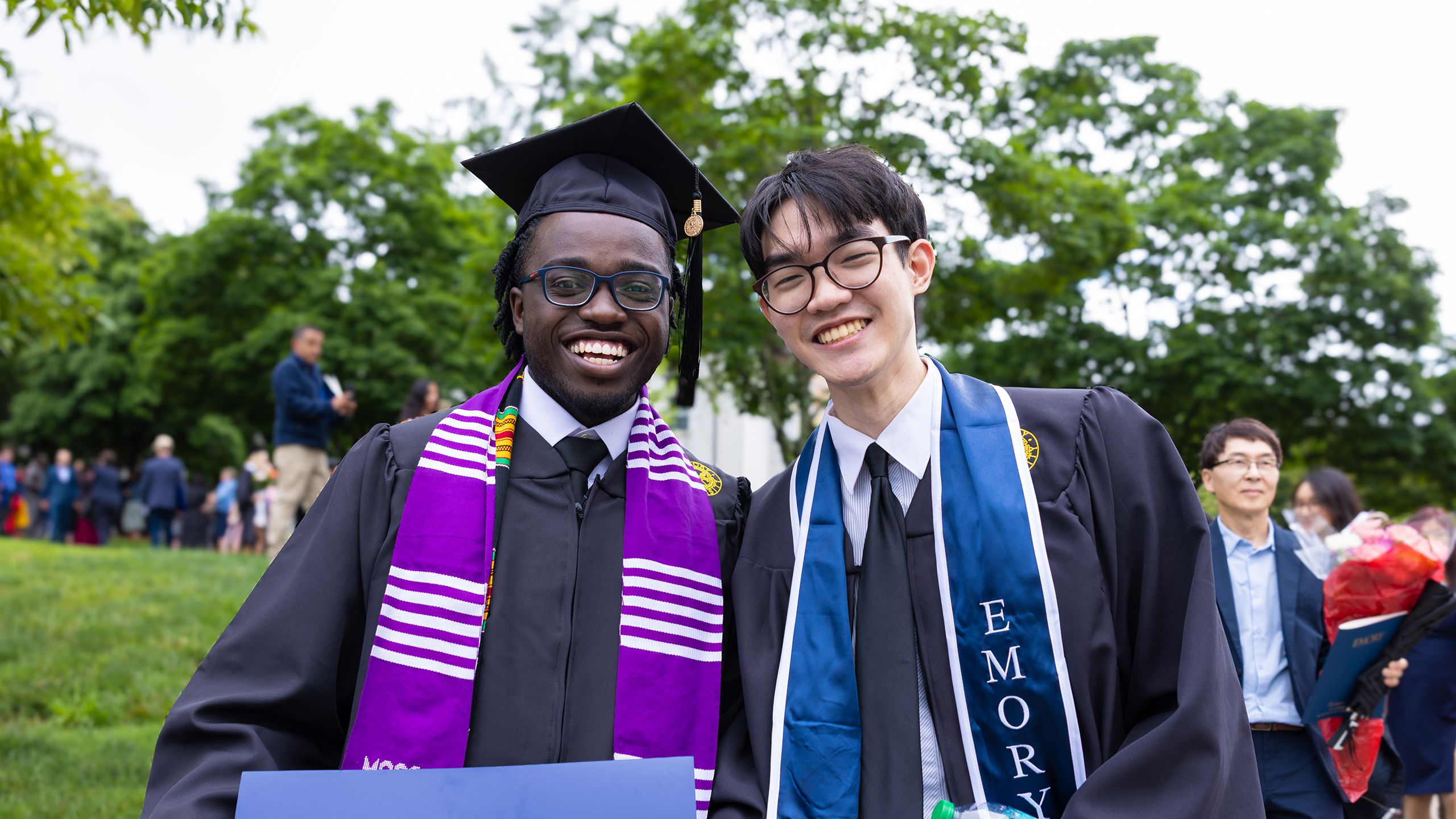 Two friends pose in graduation robes