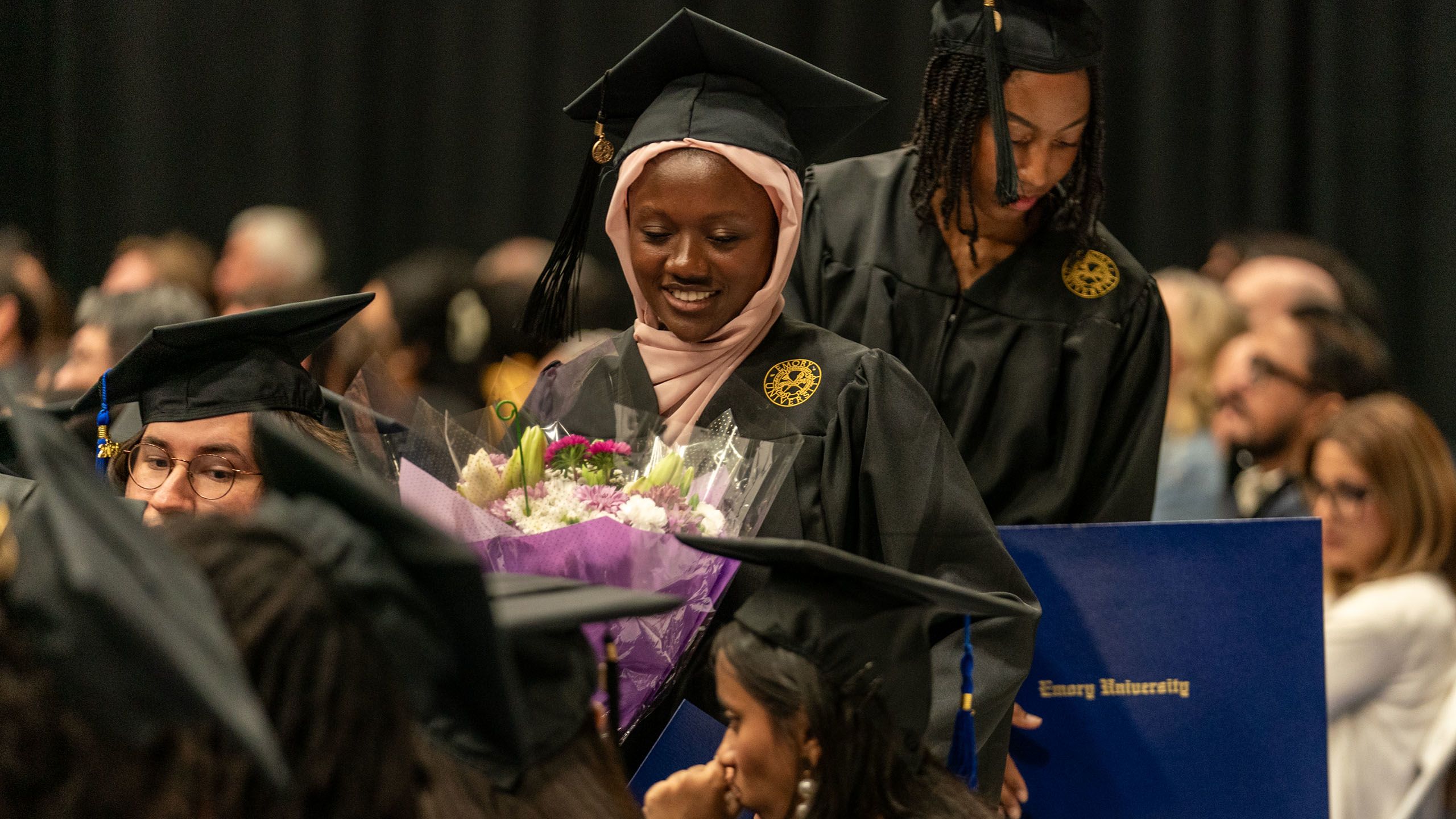 A graduate holds a bouquet of flowers