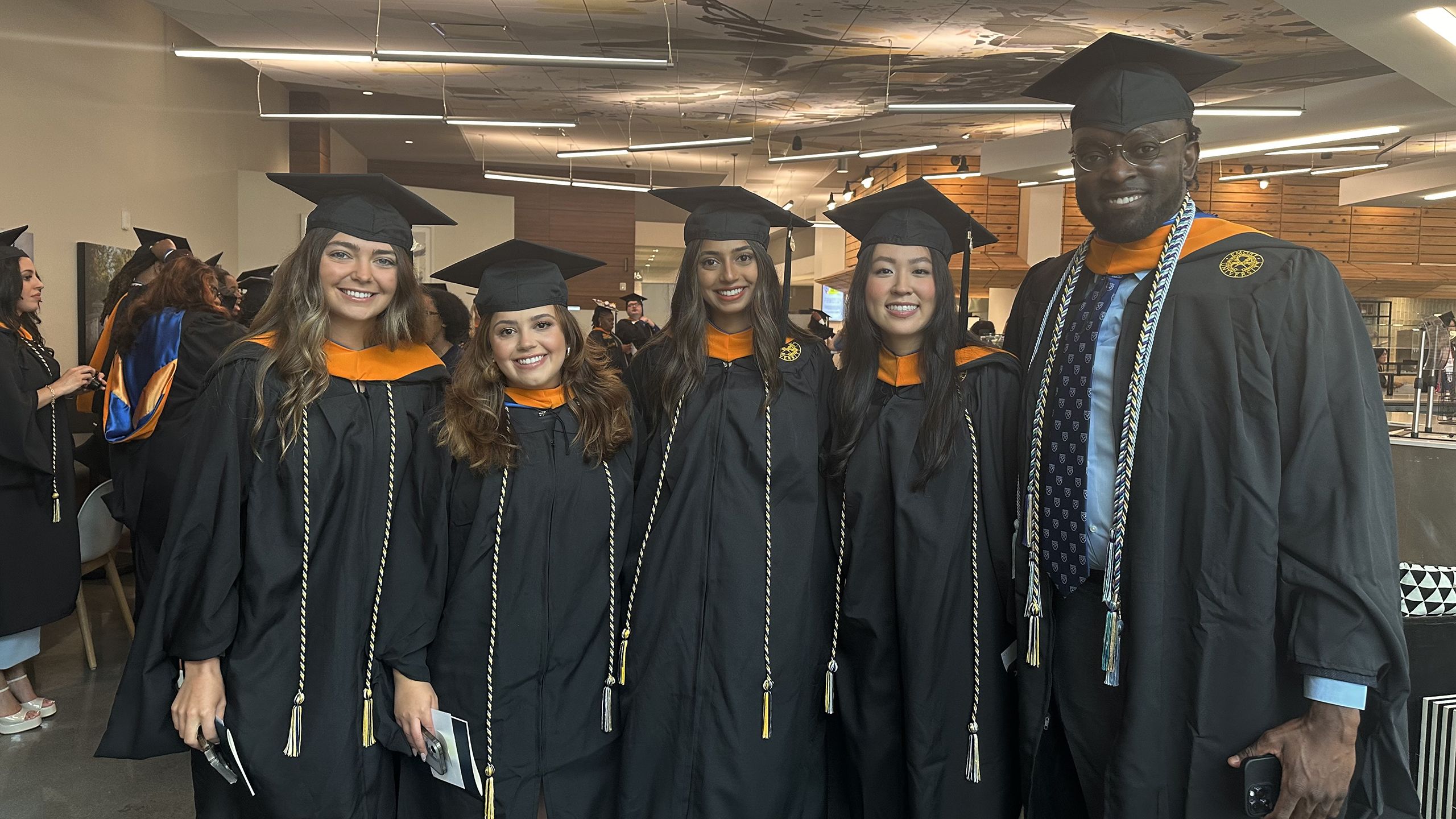 Graduates pose in gowns and cords