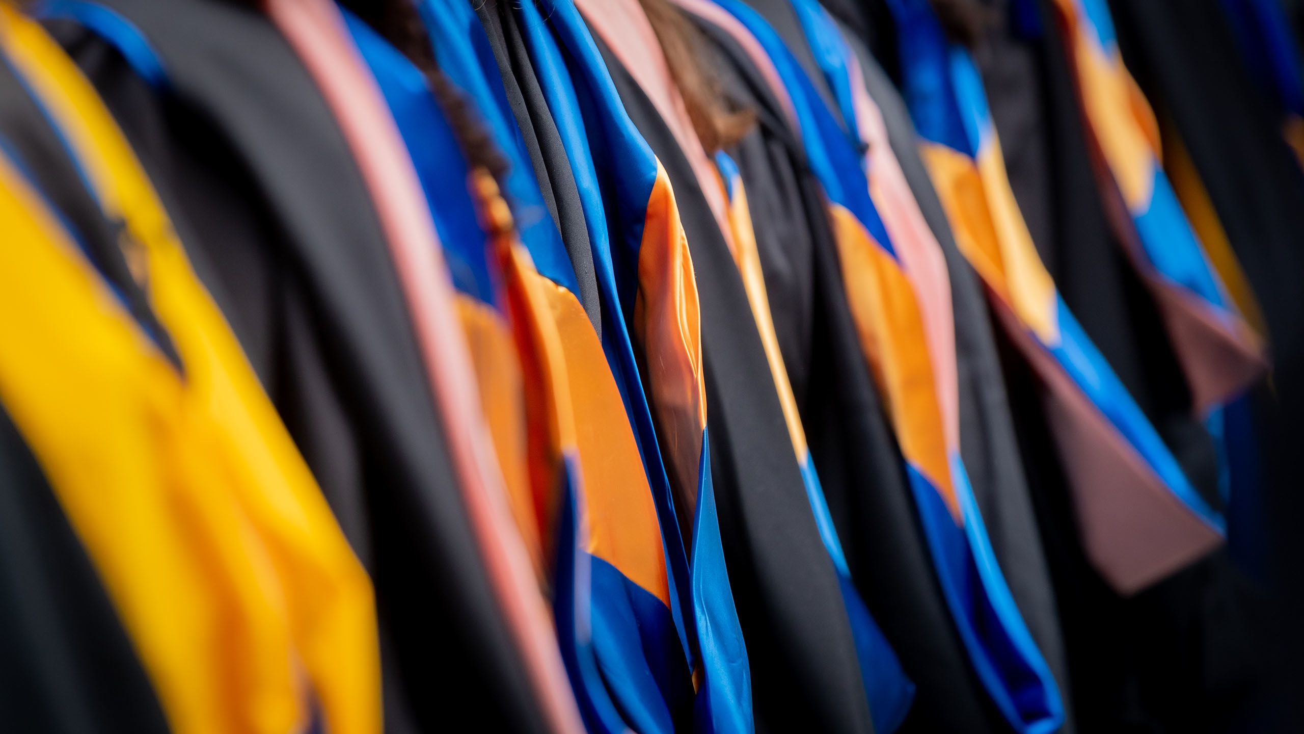 A background photo of students in caps and gowns at commencement