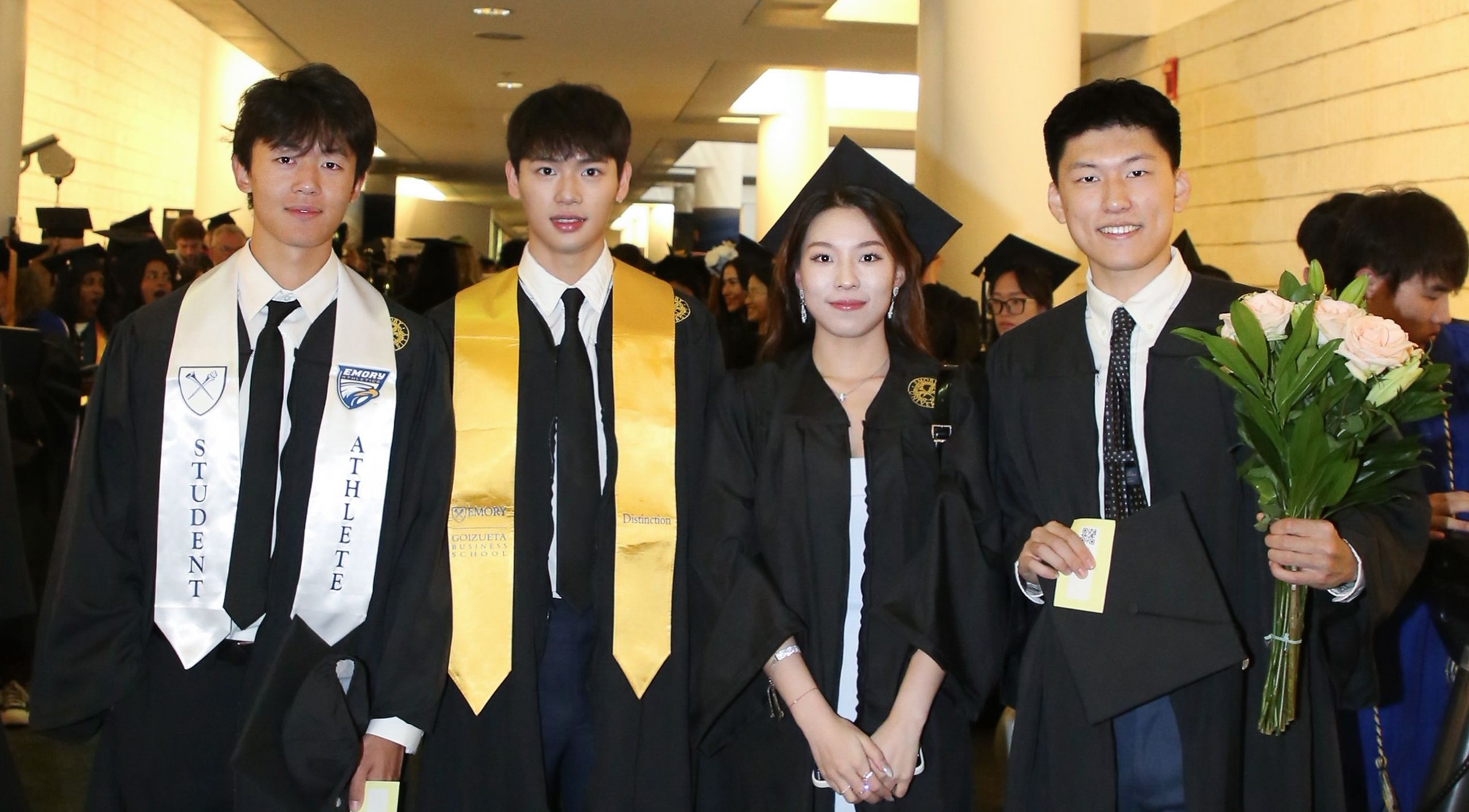 Four graduates pose in academic regalia