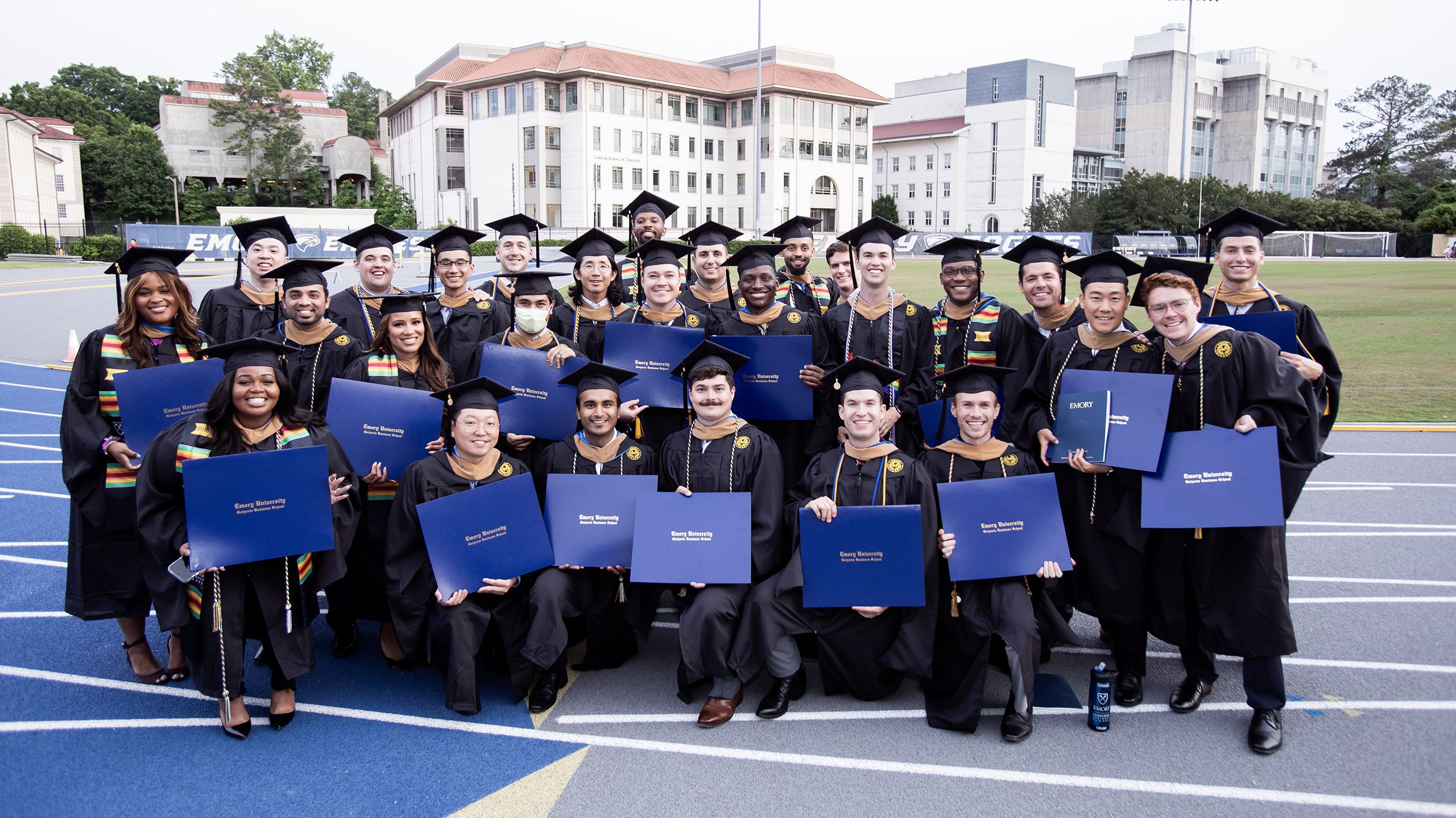 A large group of graduates pose holding their diplomas