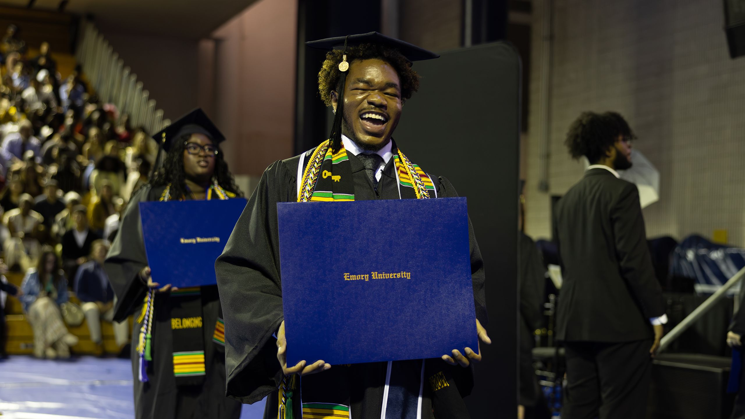 A graduate grins and holds his diploma