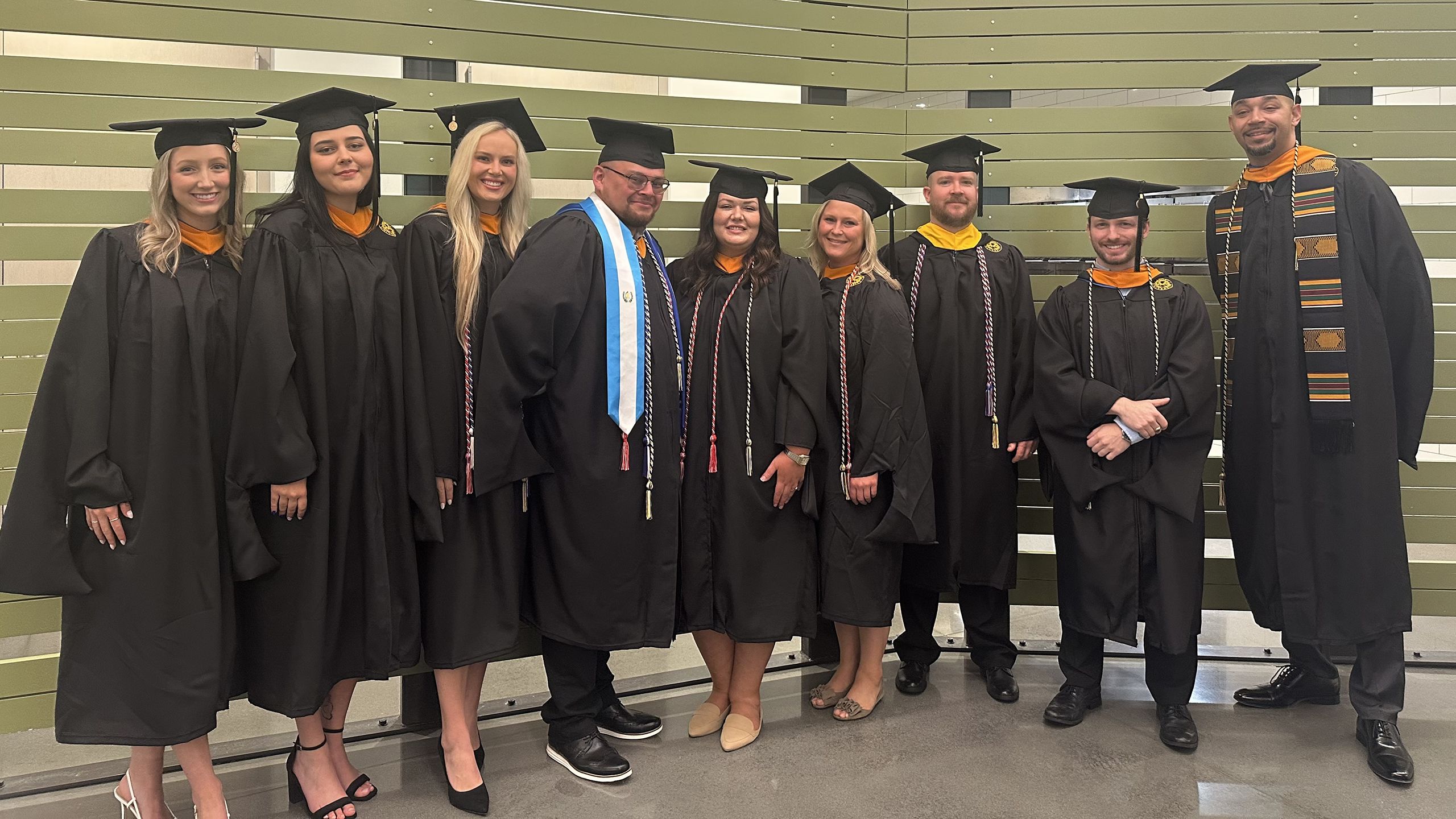 Graduates in caps and gowns pose for a photo