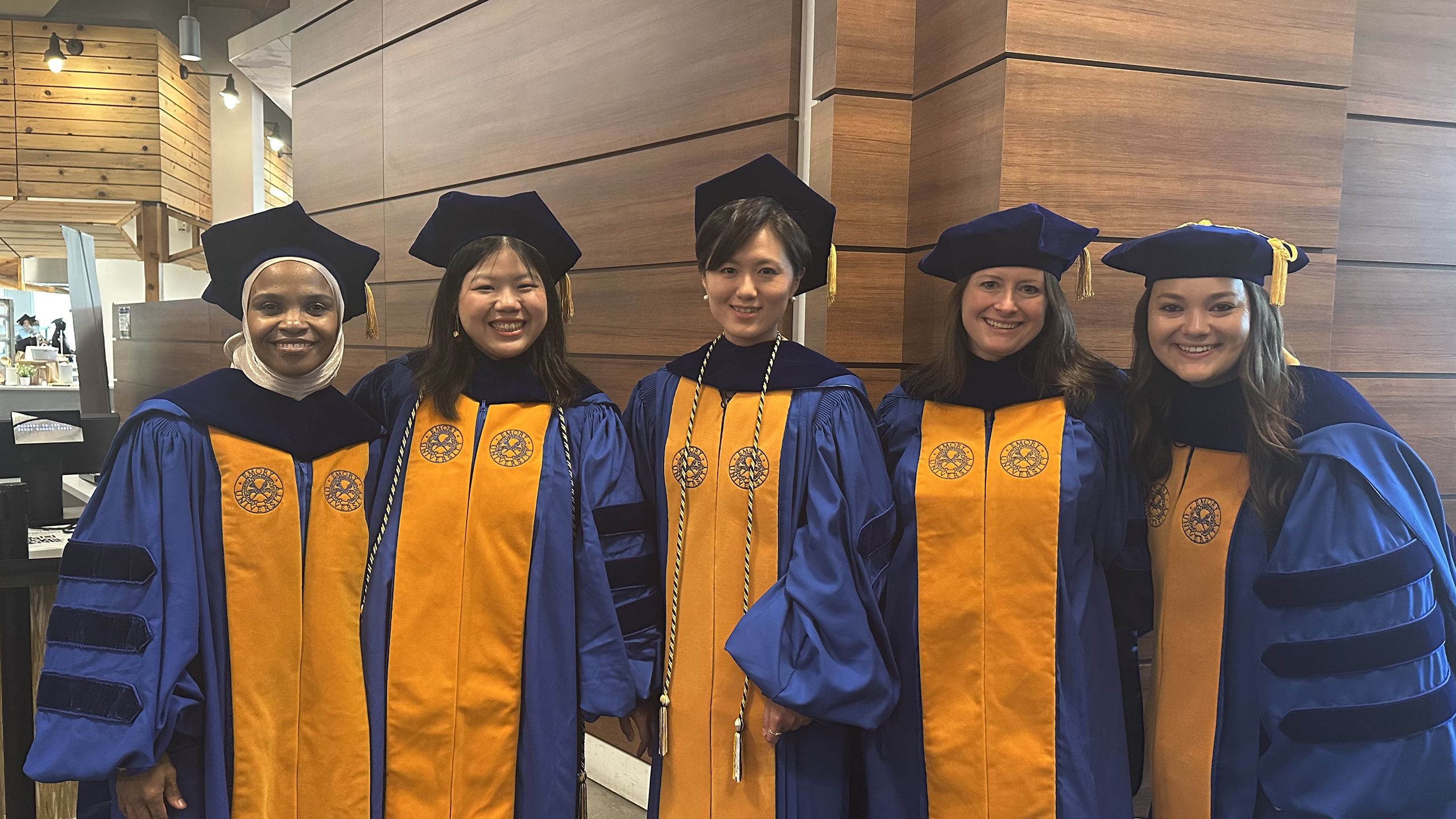 Five students in doctoral robes receiving PhDs