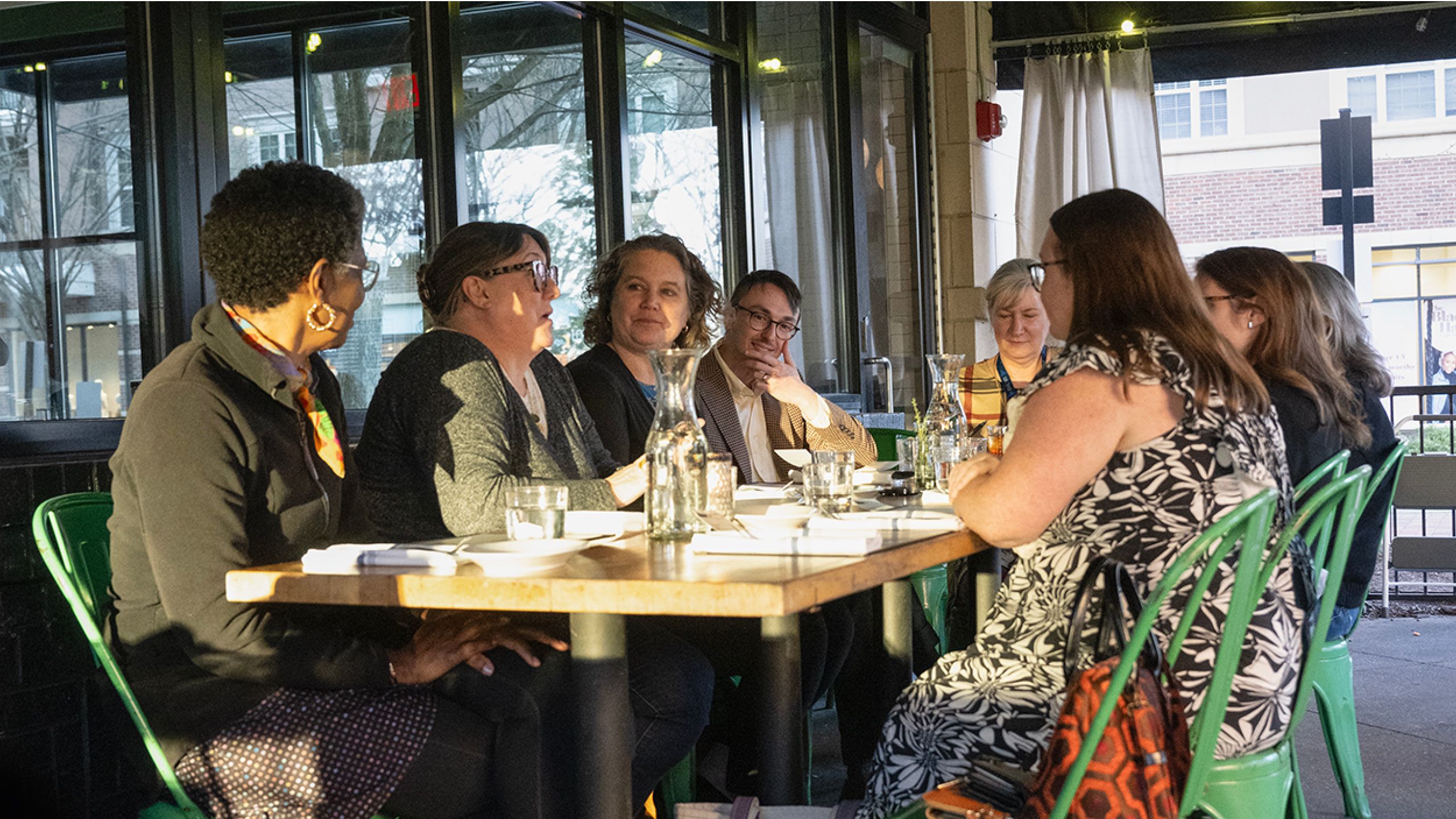 A group of eight adults sitting around a restaurant table.