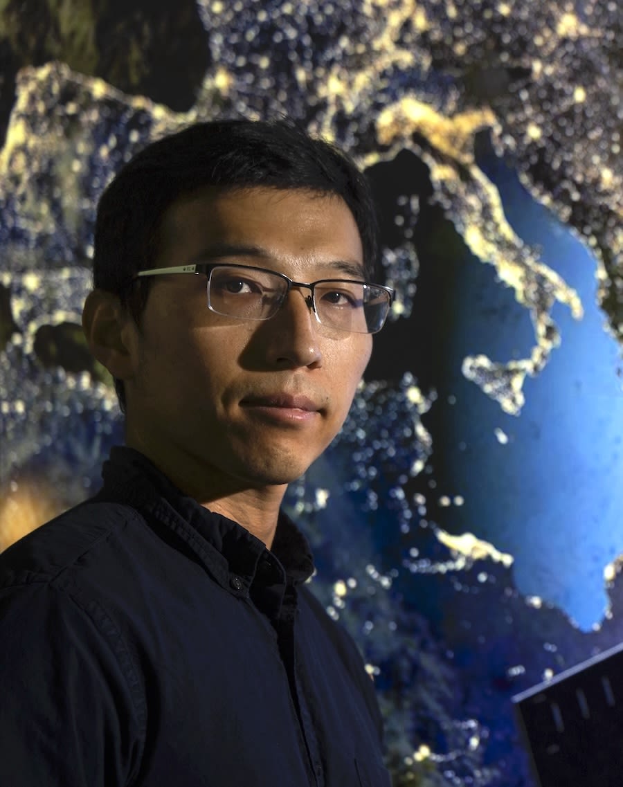 Xiao Wang stands before a world map.