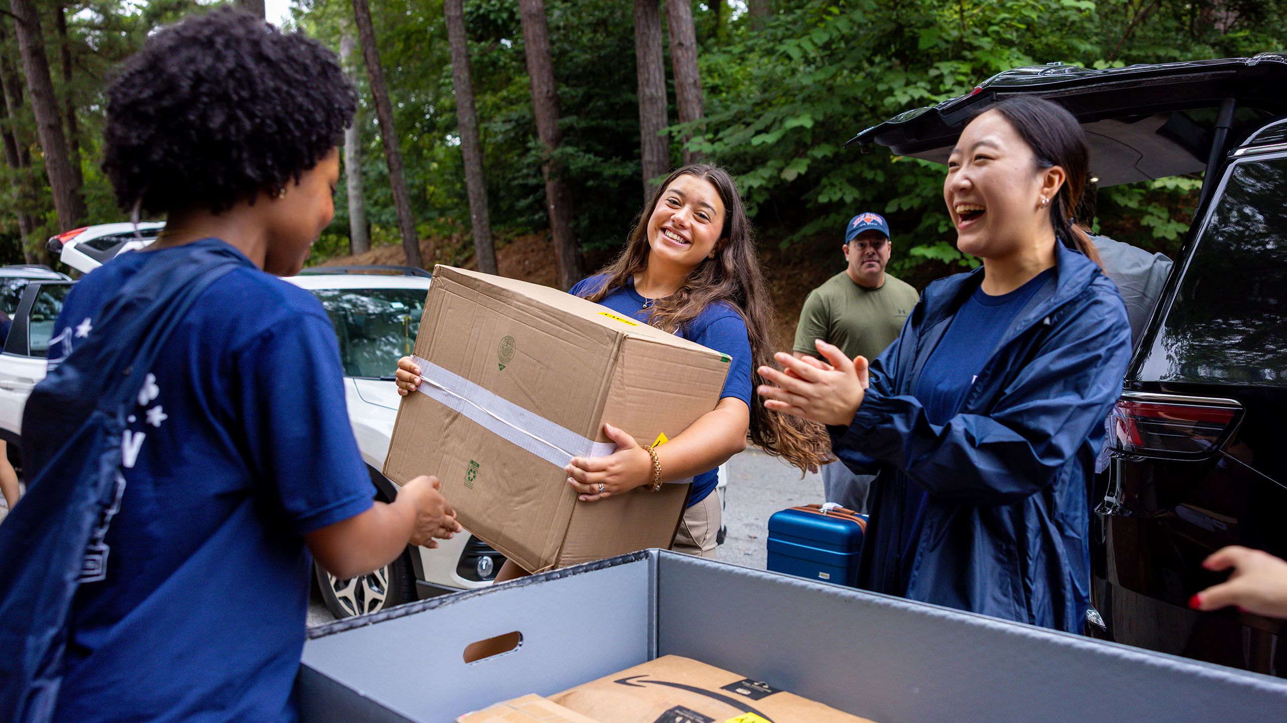 Three orientation leaders laugh while unloading a large moving cart