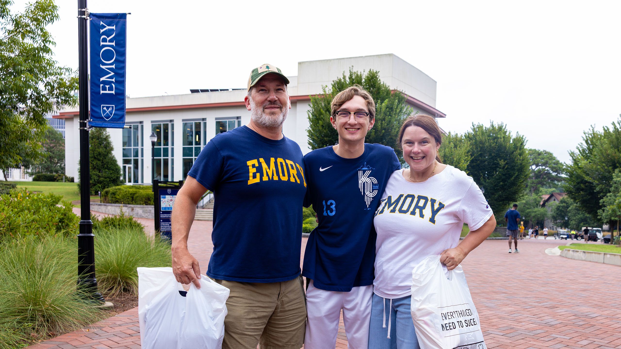 A male student flanked by his parents, both wearing Emory shirts.