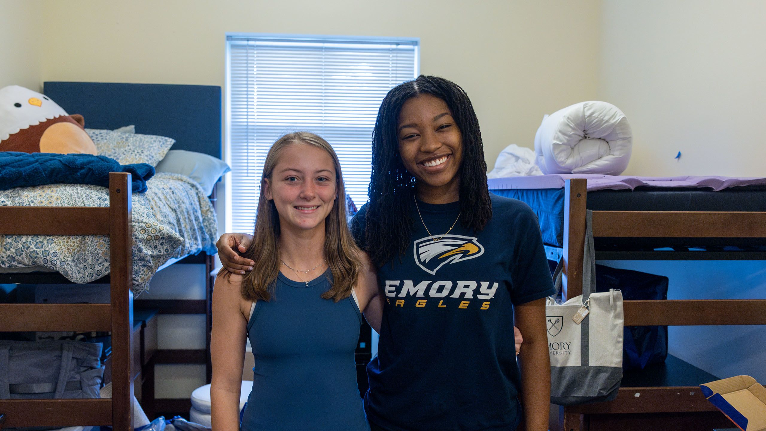 two female roommates standing in their new residence hall, smiling