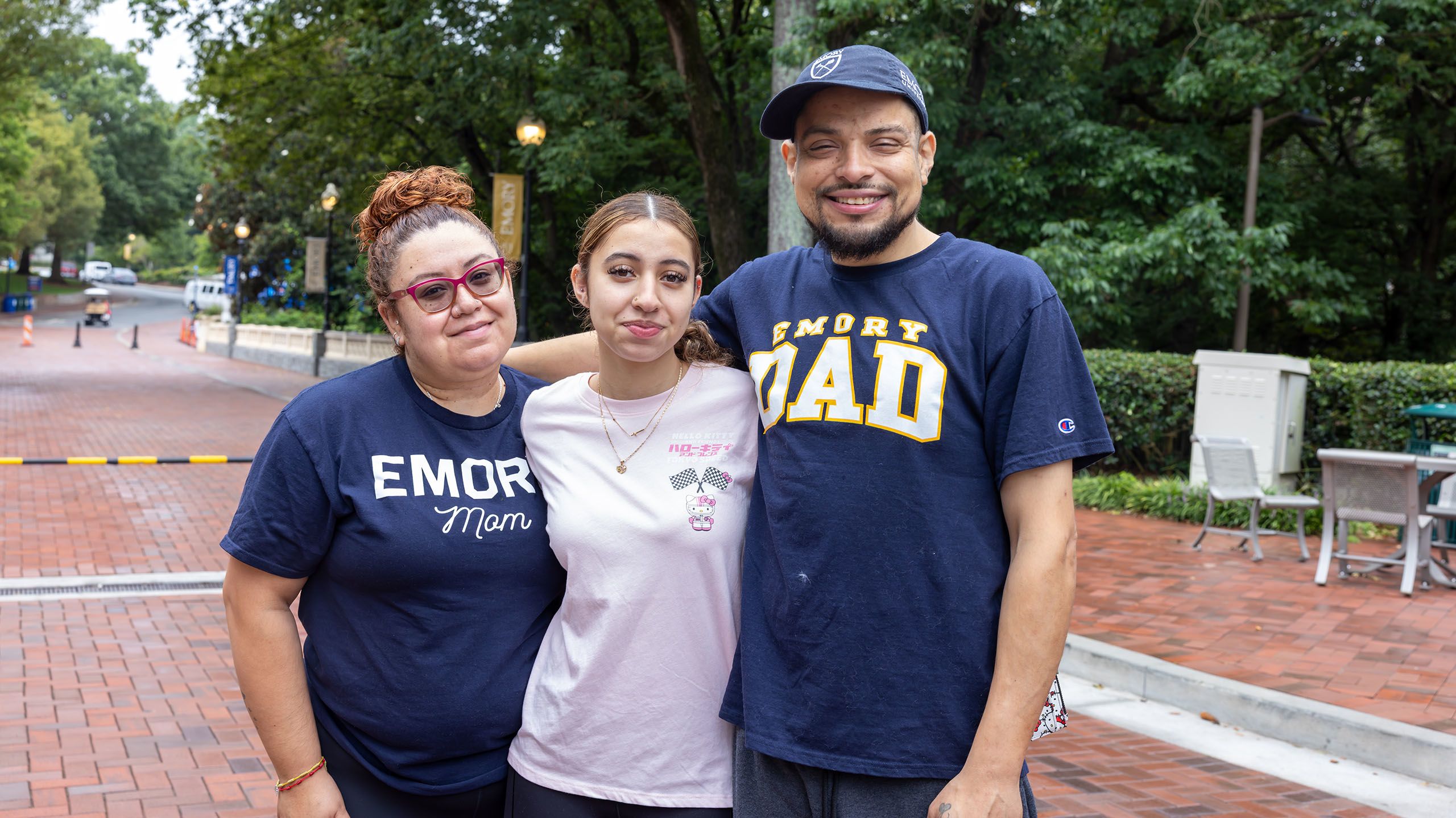 An incoming student, flanked by her parents, wearing Emory Mom and Emory Dad shirts