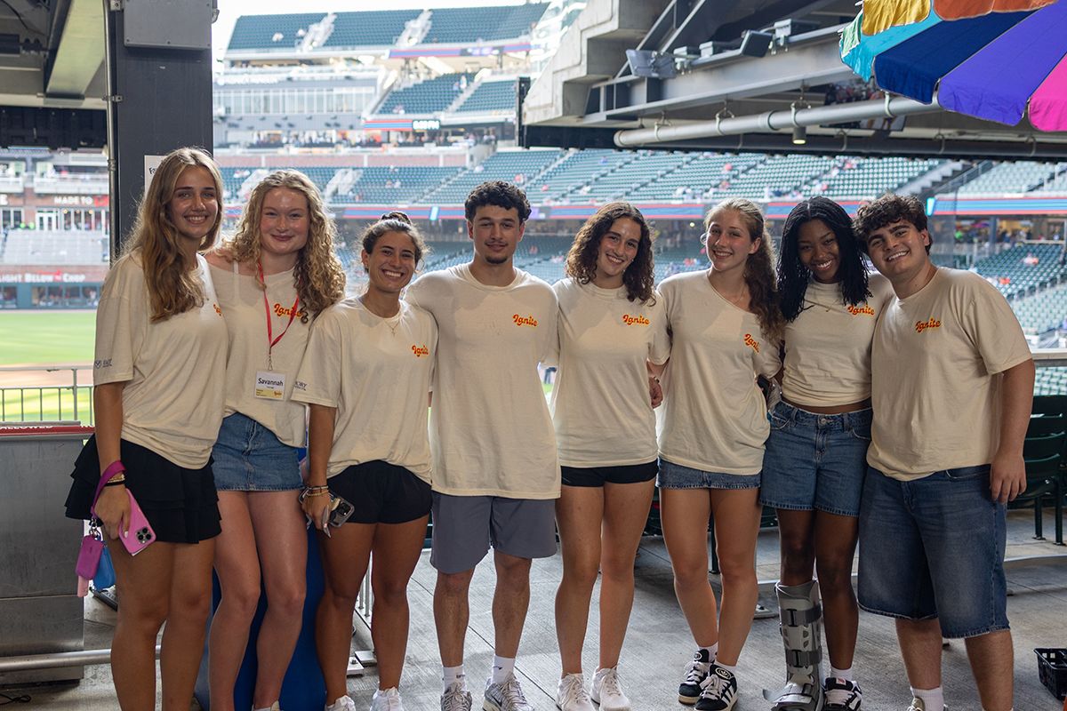 Large group of students, wearing matching shirts that say Ignite, smile at the Atlanta Braves baseball stadium