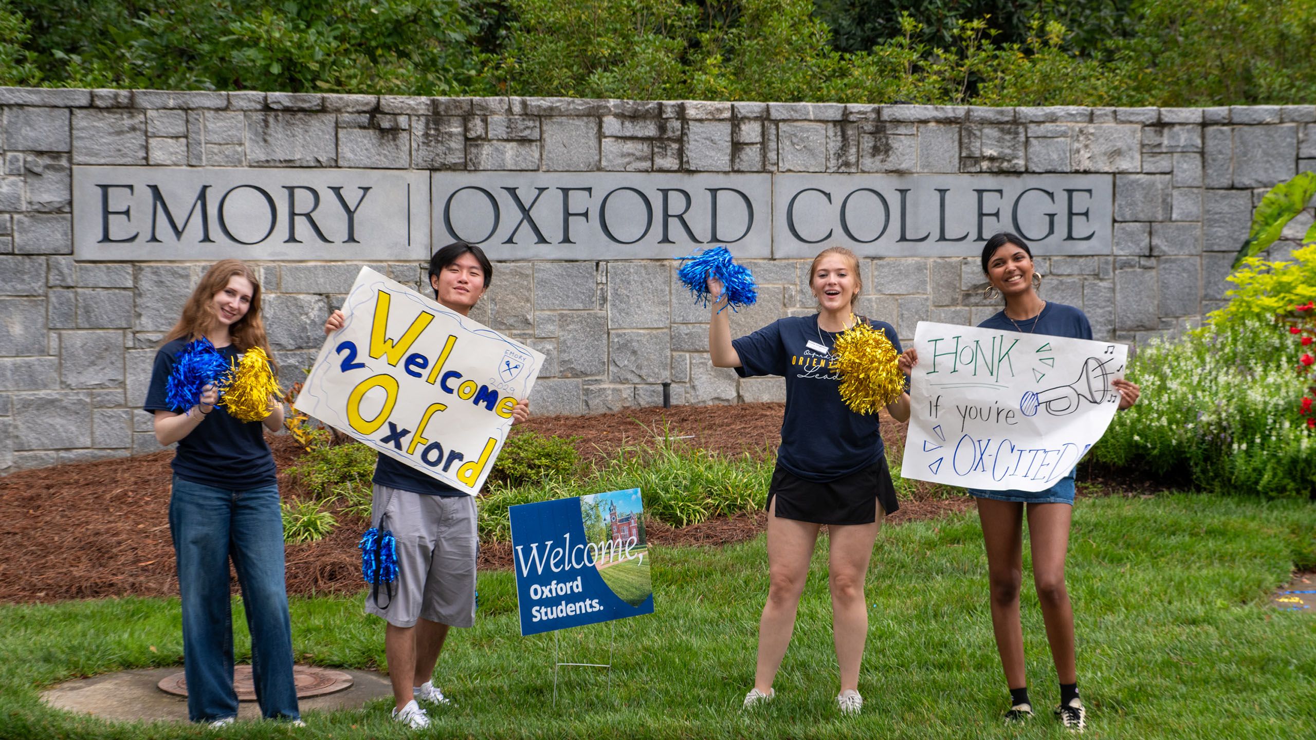 Orientation leaders hold signs saying Welcome to Oxford and waving blue and gold pom poms