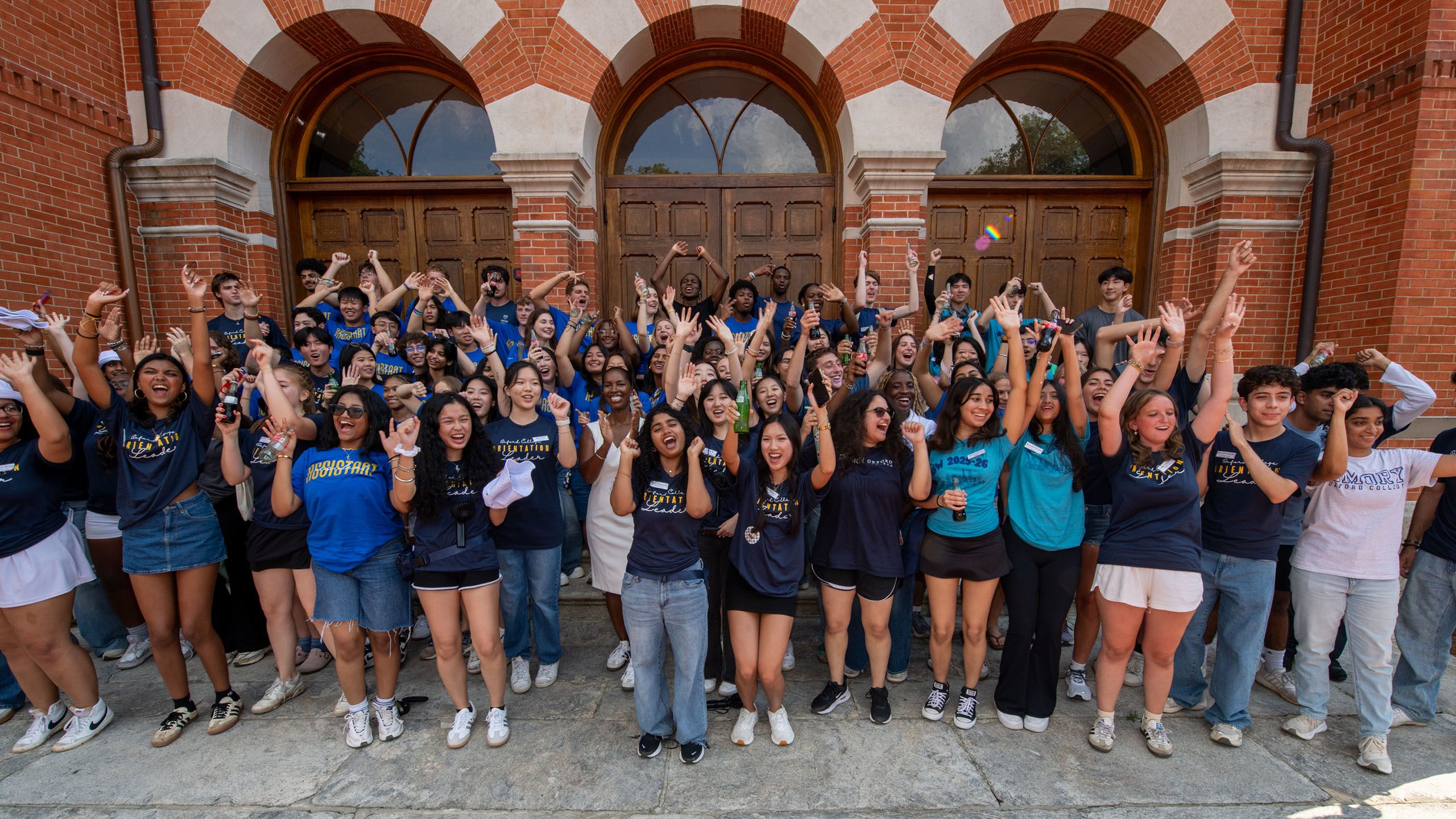 Large group of Oxford orientation leaders cheer in front of Seney Hall, alongside Dean Badia Ahad
