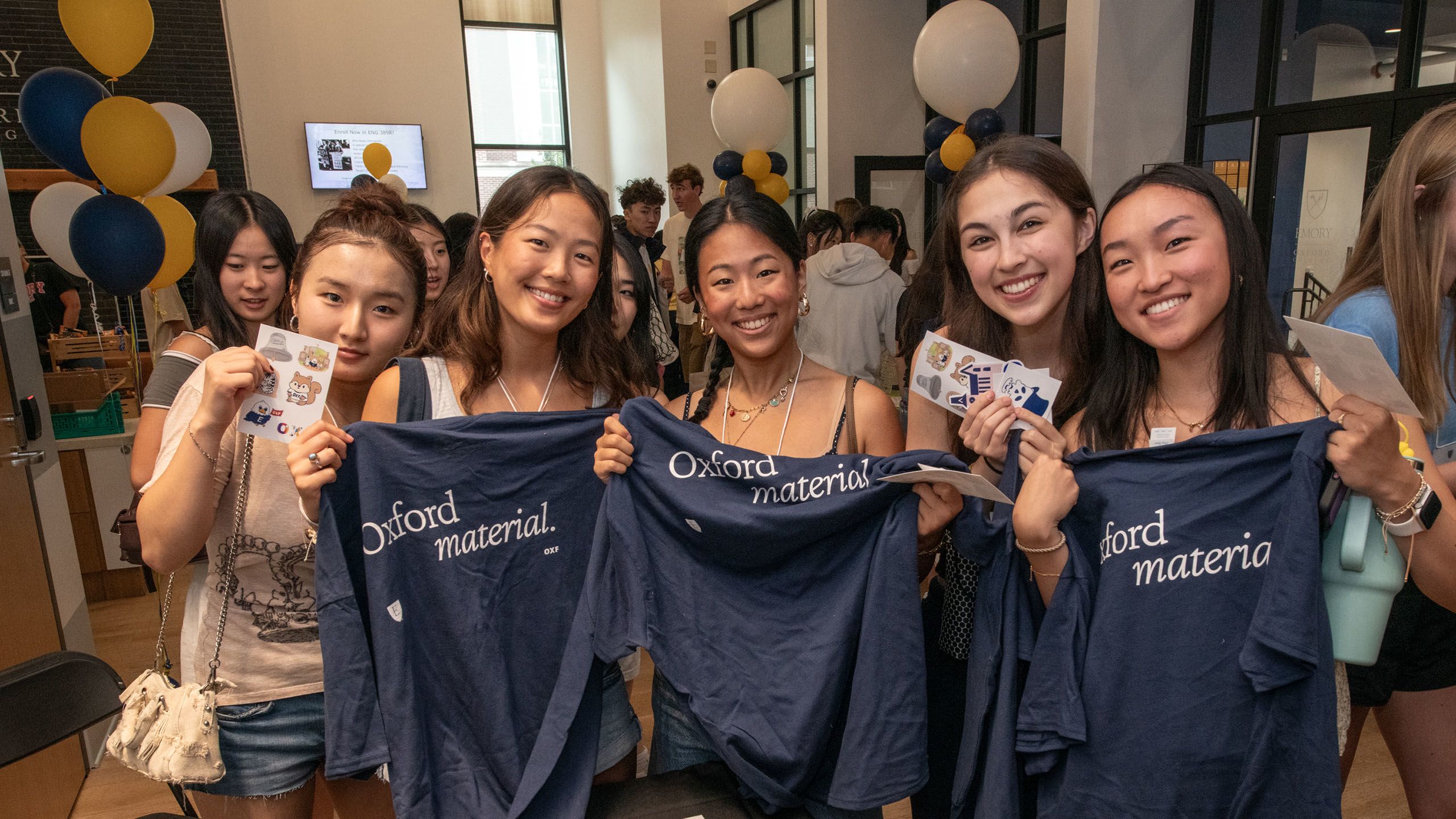 A group of five students hold up matching shirts reading Oxford Material
