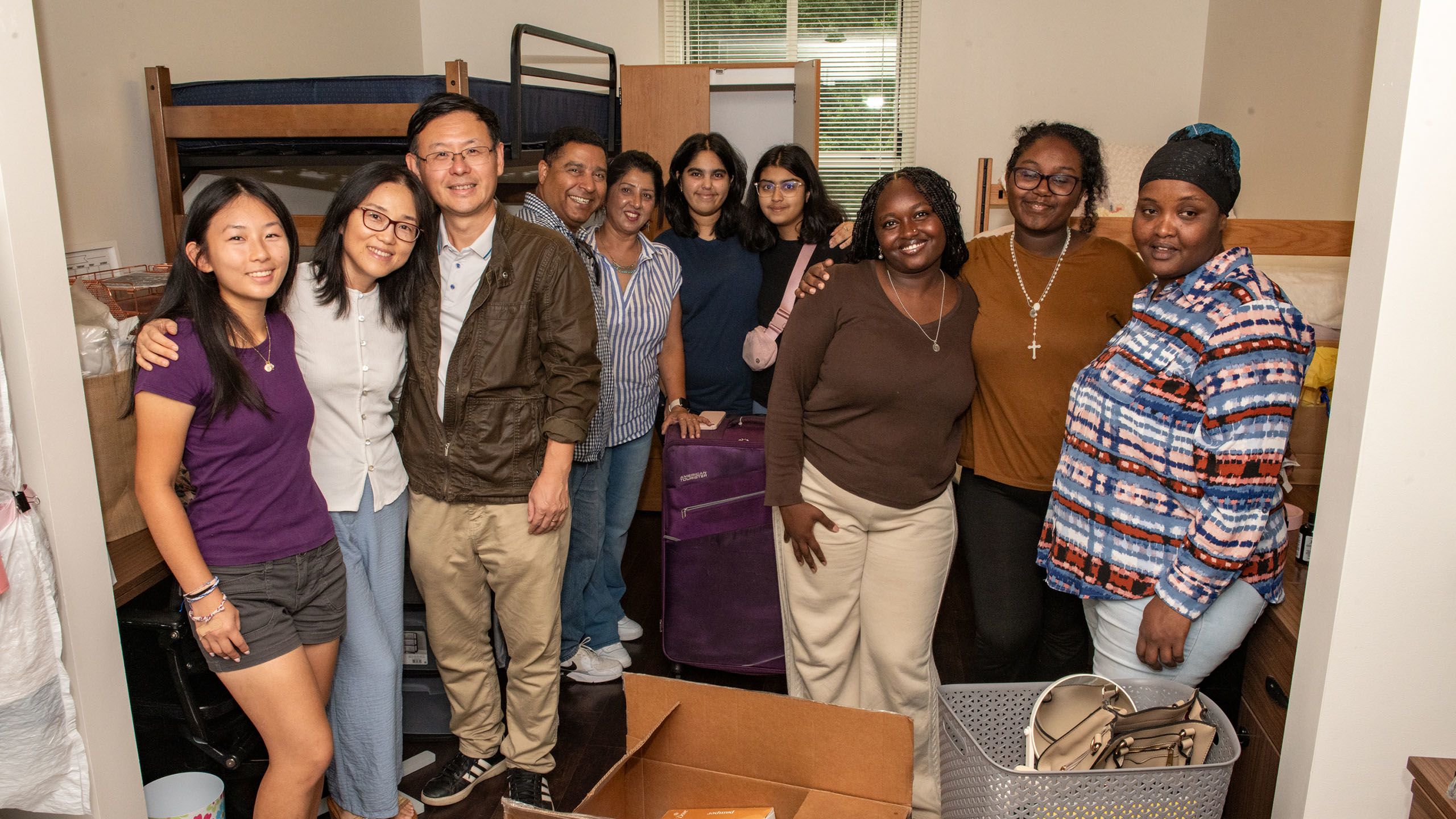 Two families, posing together and smiling in their daughters' new room