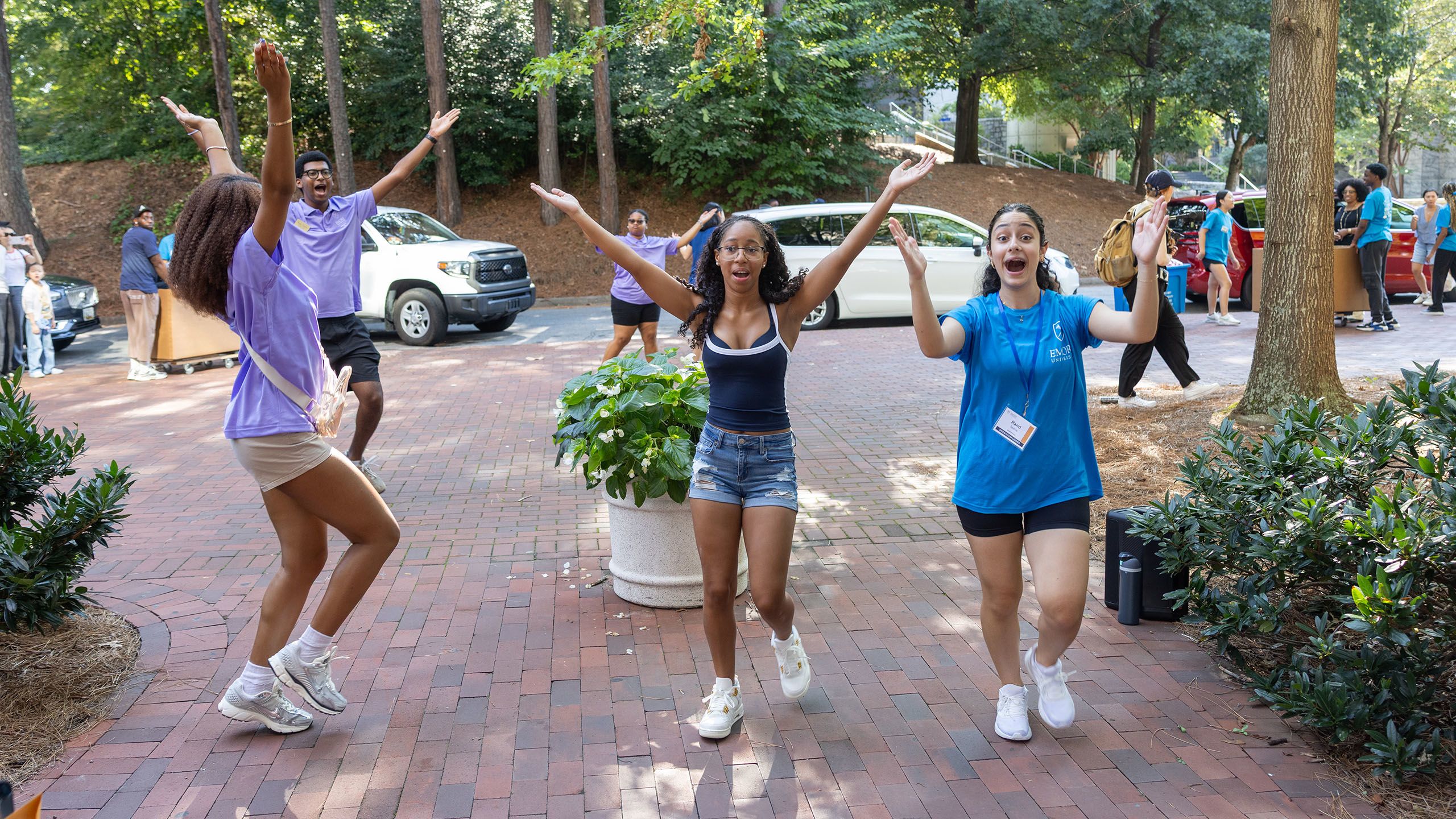 four students throw their hands up, waving