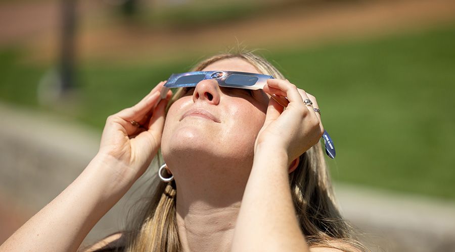 Girl looking up at the sun with solar glasses