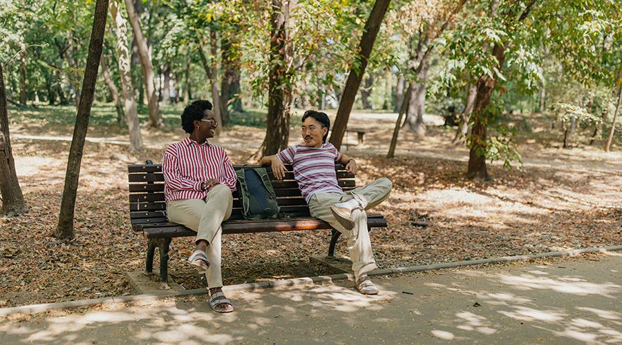 Man and woman on park bench enjoying a shady chat