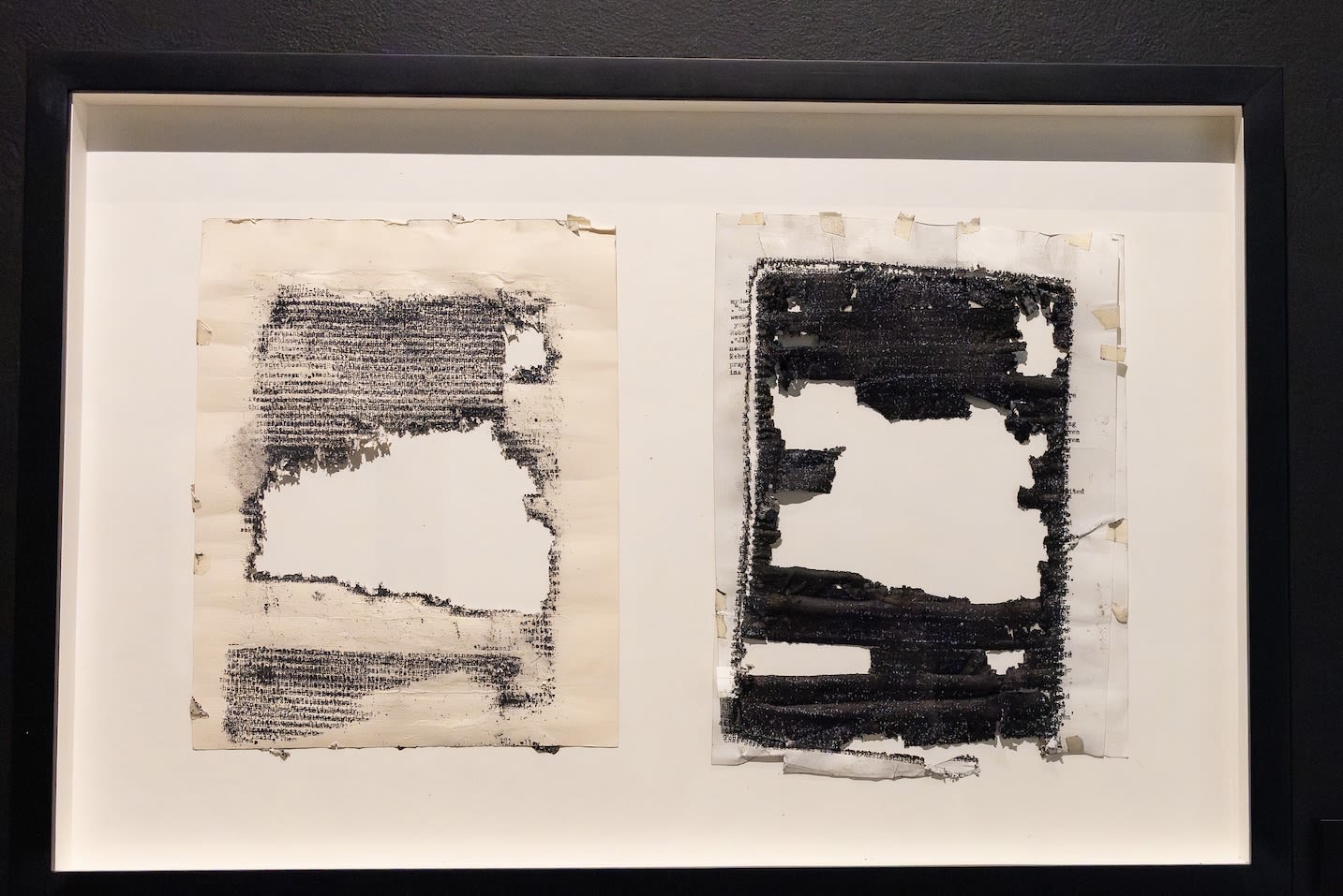 Two pages laid out next to each other form a diptych. The sheet on the right is covered with black typewriter ink and has several holes in it, including a large one at the center. The ink on the sheet on the left is less dark, but it also has a large hole in the center.