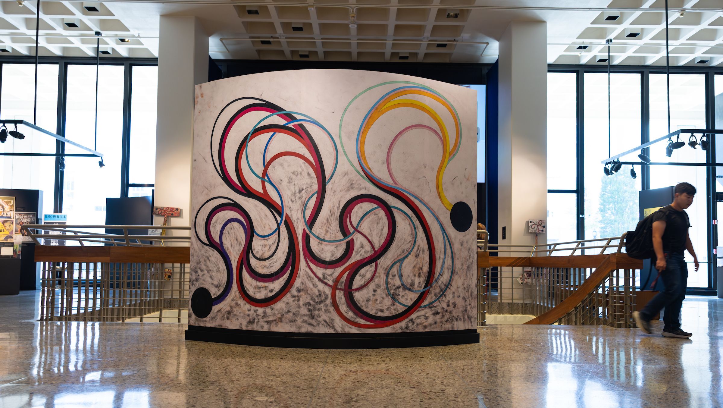 A larger-than-life painting of colorful, uncoiling lines connected by black dots