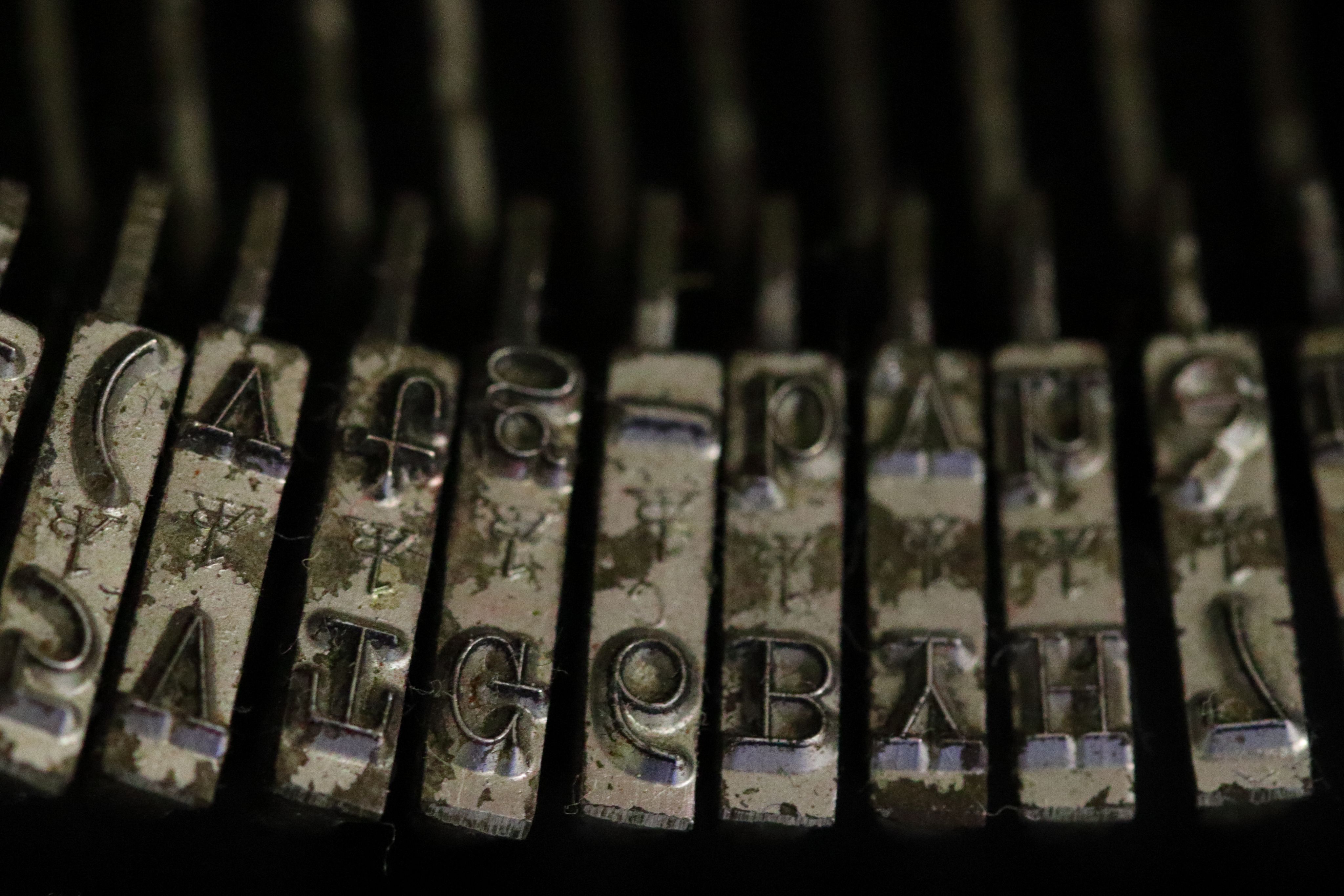 A close-up view of a set of typewriter type bars, with upper and lowercase letters visible.