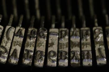 A close-up view of a set of typewriter type bars, with upper and lowercase letters visible.