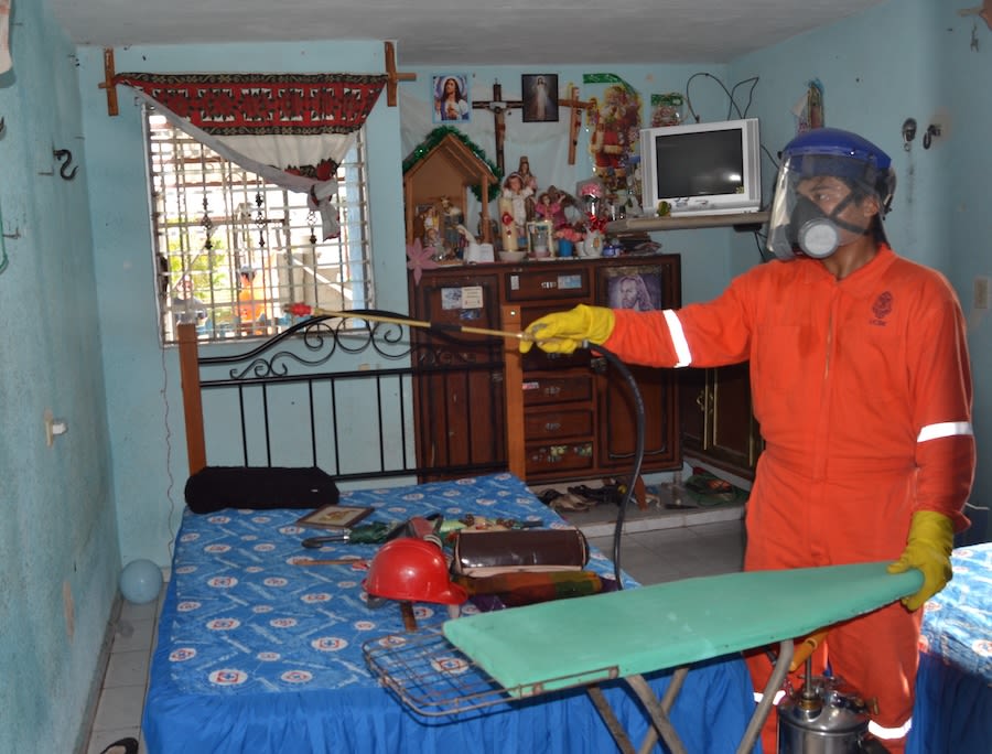 A health official sprays for mosquitos inside a home.