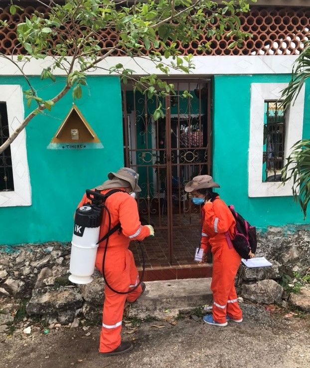 Public health workers prepare to enter a resident to treat it for mosquitos