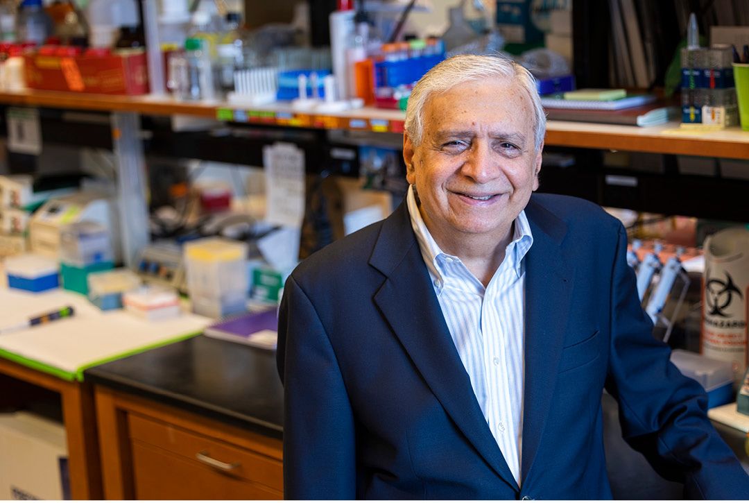 A shot of Rafi Ahmed, a man with gray hair in a navy jacket, standing in a lab.