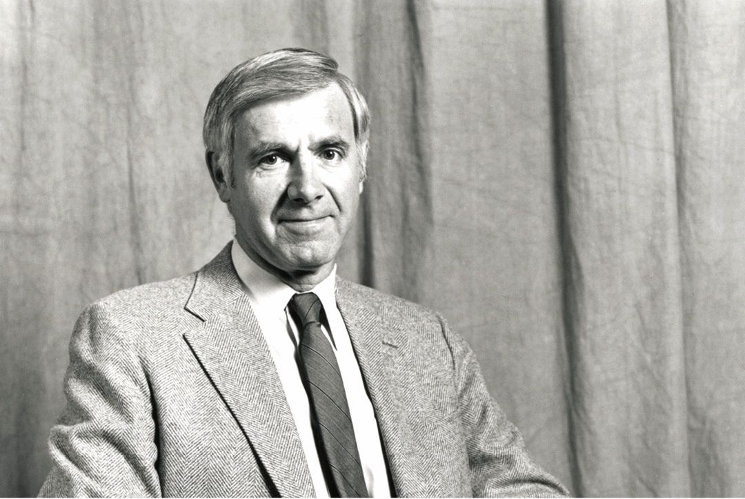 Portrait of William Foege, a white man with salt and pepper hair in a coat and tie.