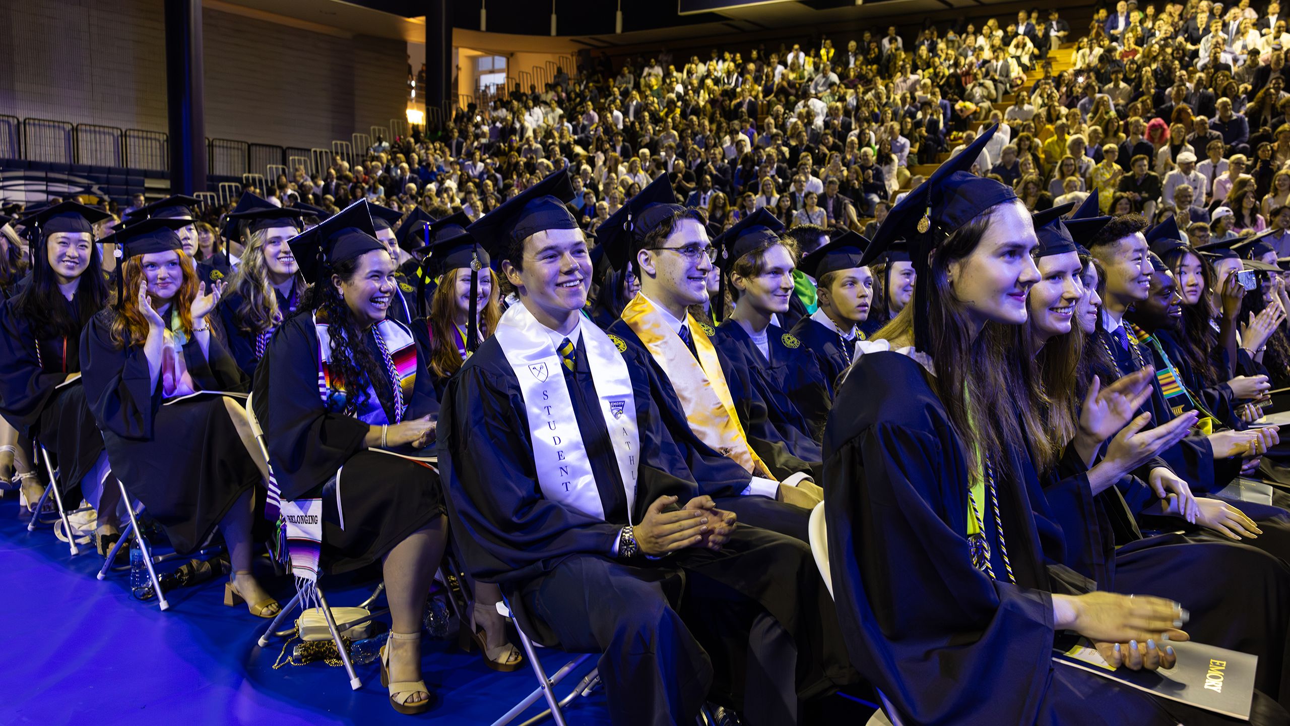 Graduates in regalia sit in rows at Commencement