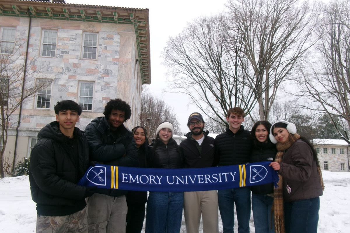 Students hold an Emory scarf in the snow