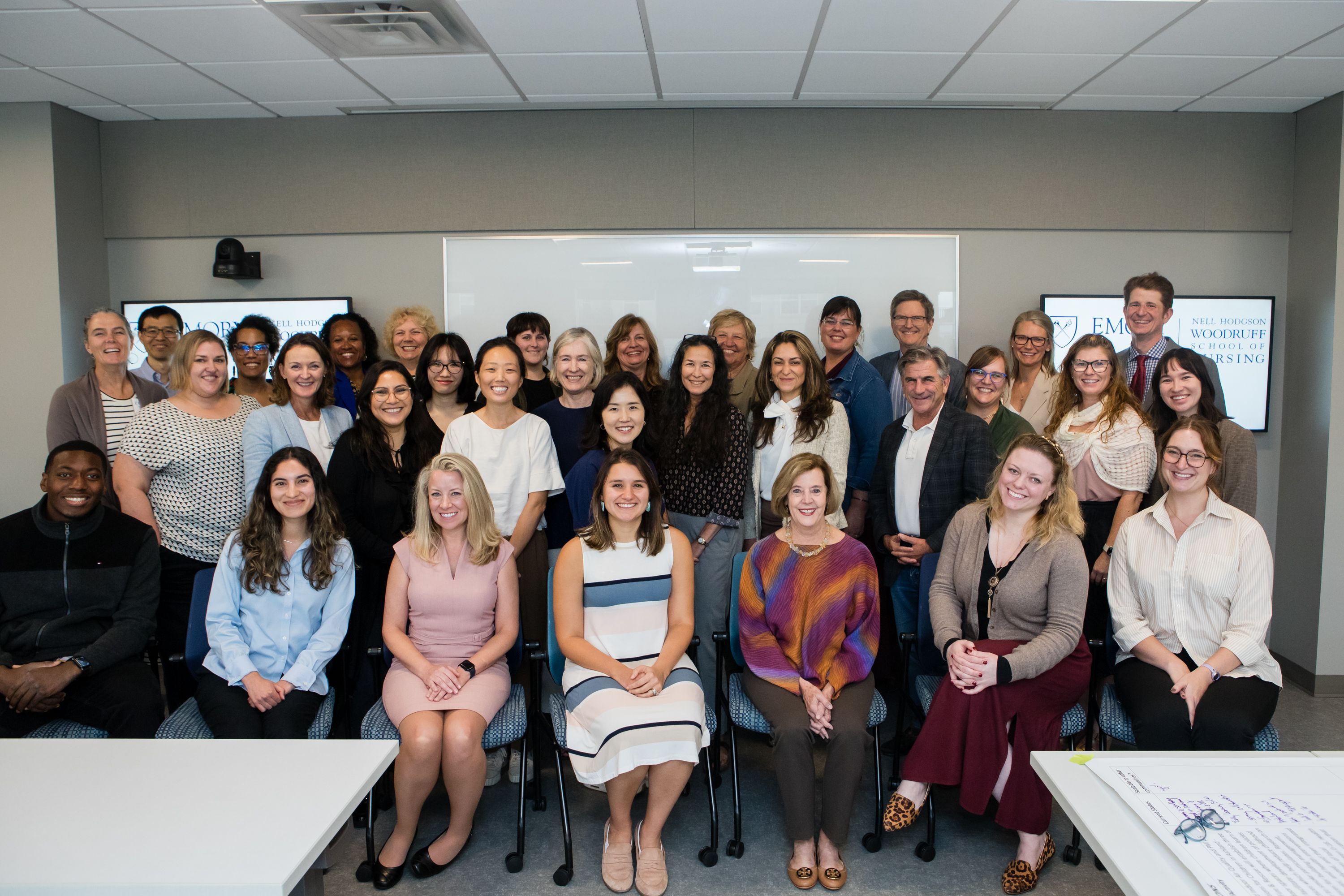 Group photo of about 20 people sitting and standing at the front of a classroom.