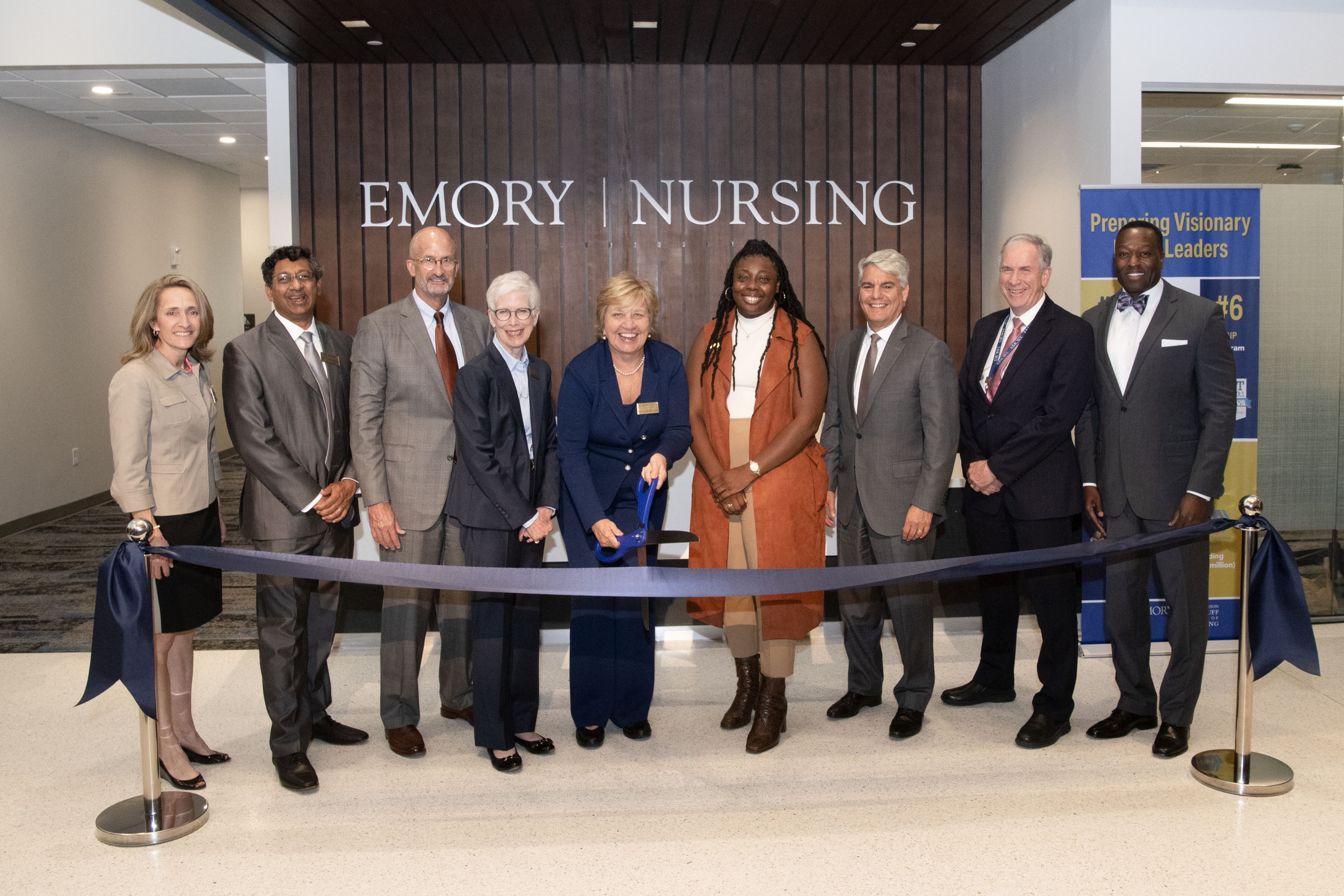 A group of leaders in front of a ribbon. Dean McCauley holds a large pair of ceremonial scissors with blue handles.