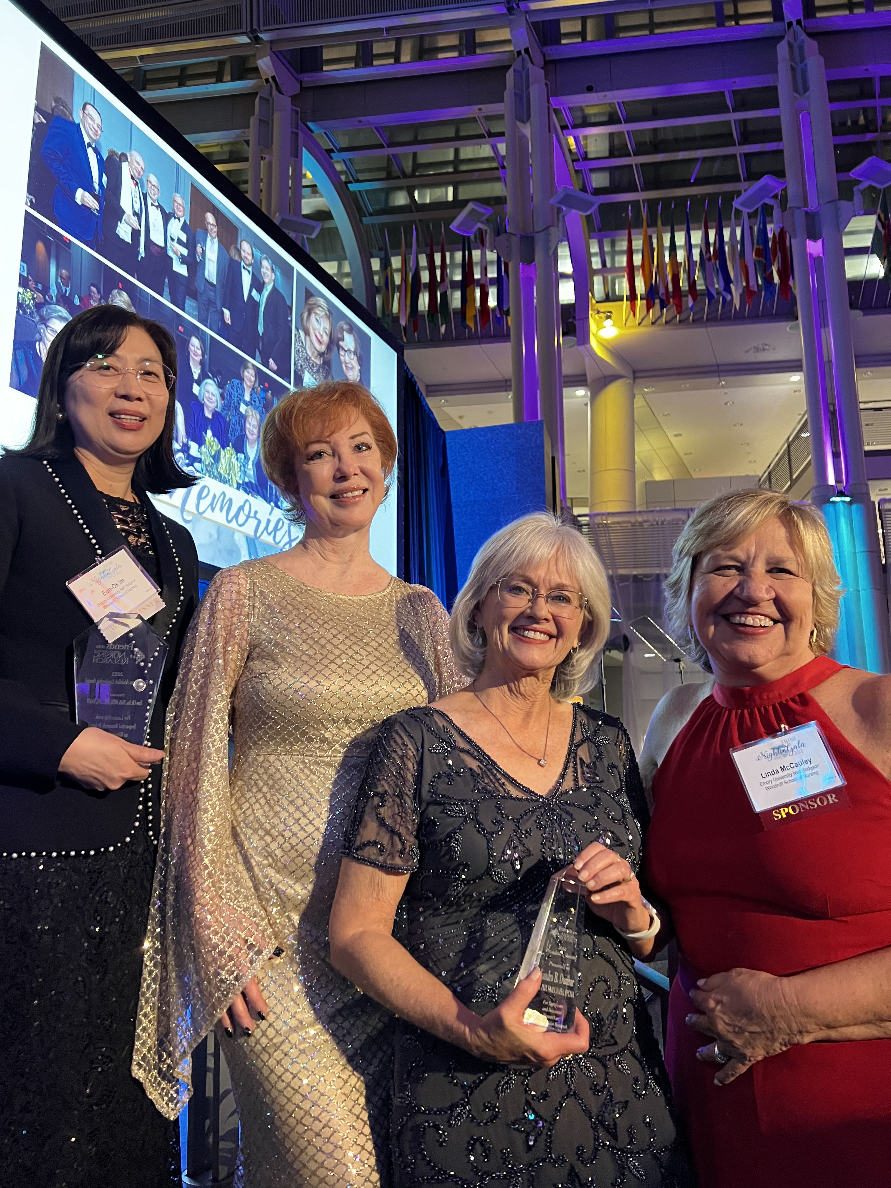 Four nursing faculty members (including Dean McCauley) at a reception, in evening dress. Two of them are holding awards.